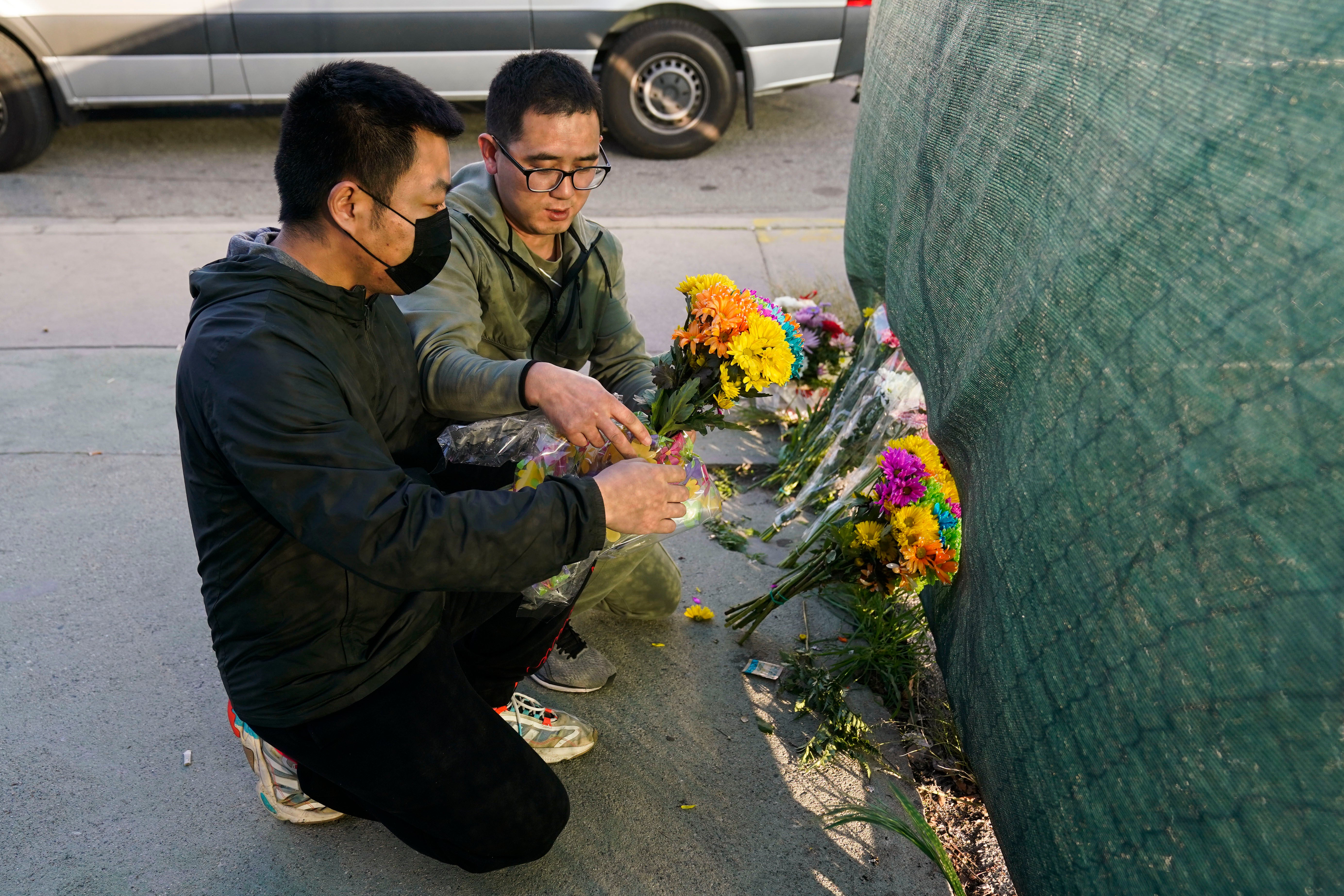 Two men place flowers near Star Dance Studio to honor victims killed in a shooting in Monterey Park