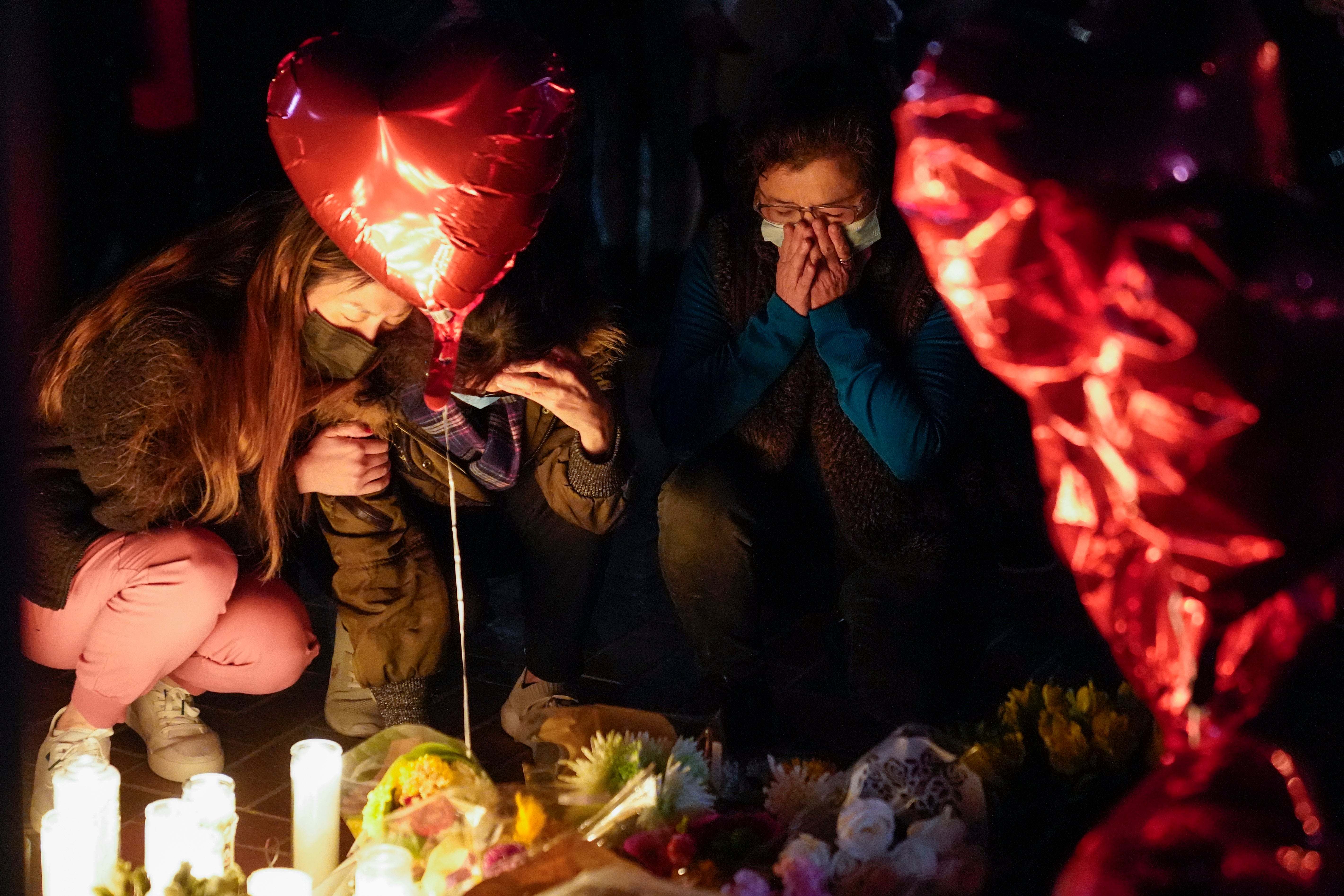 Women pause at a memorial at a vigil honoring the victims of a shooting at the Star Ballroom Dance Studio