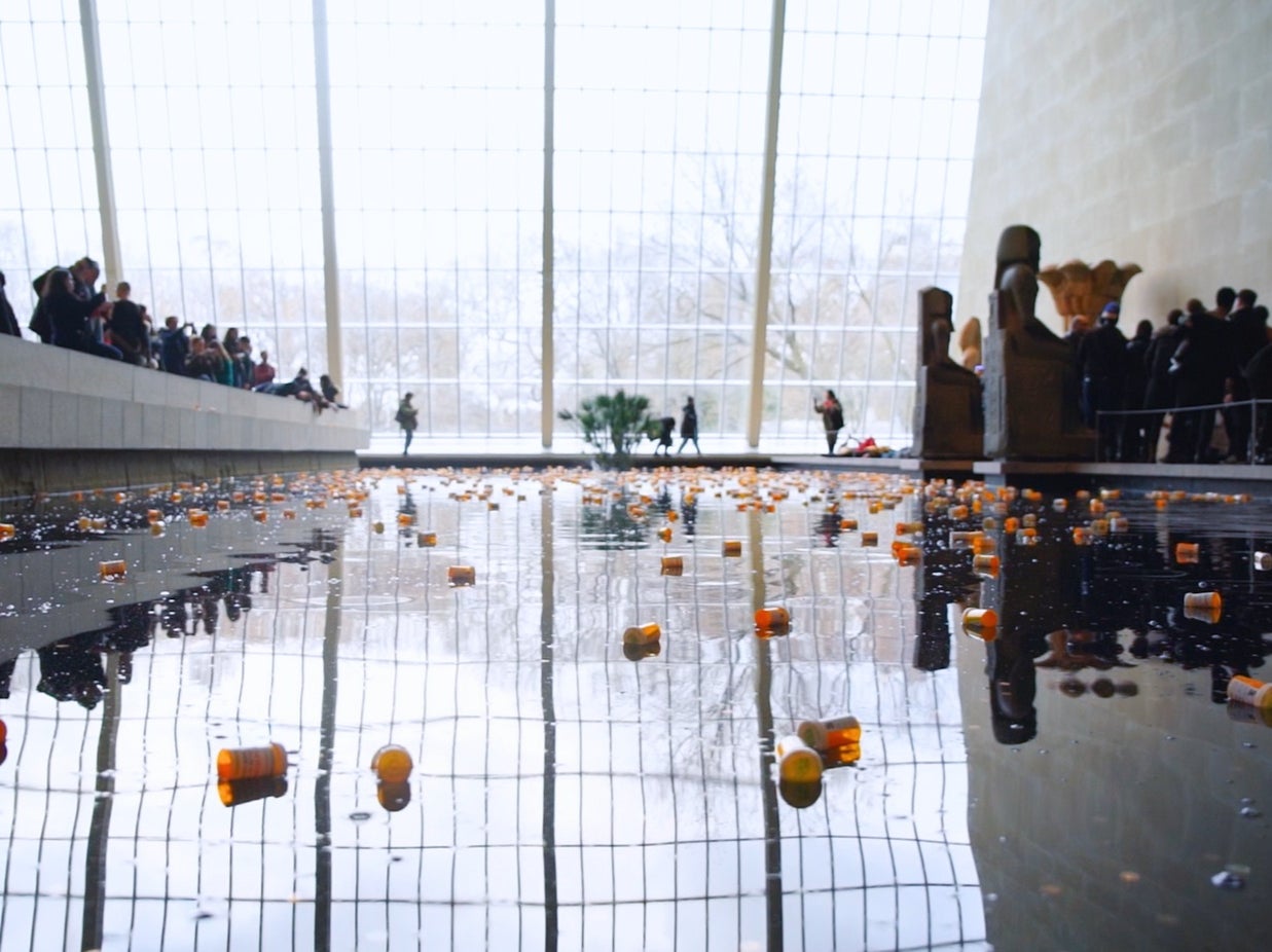 Pill bottles float in a decorate water feature as part of one of PAIN’s protests