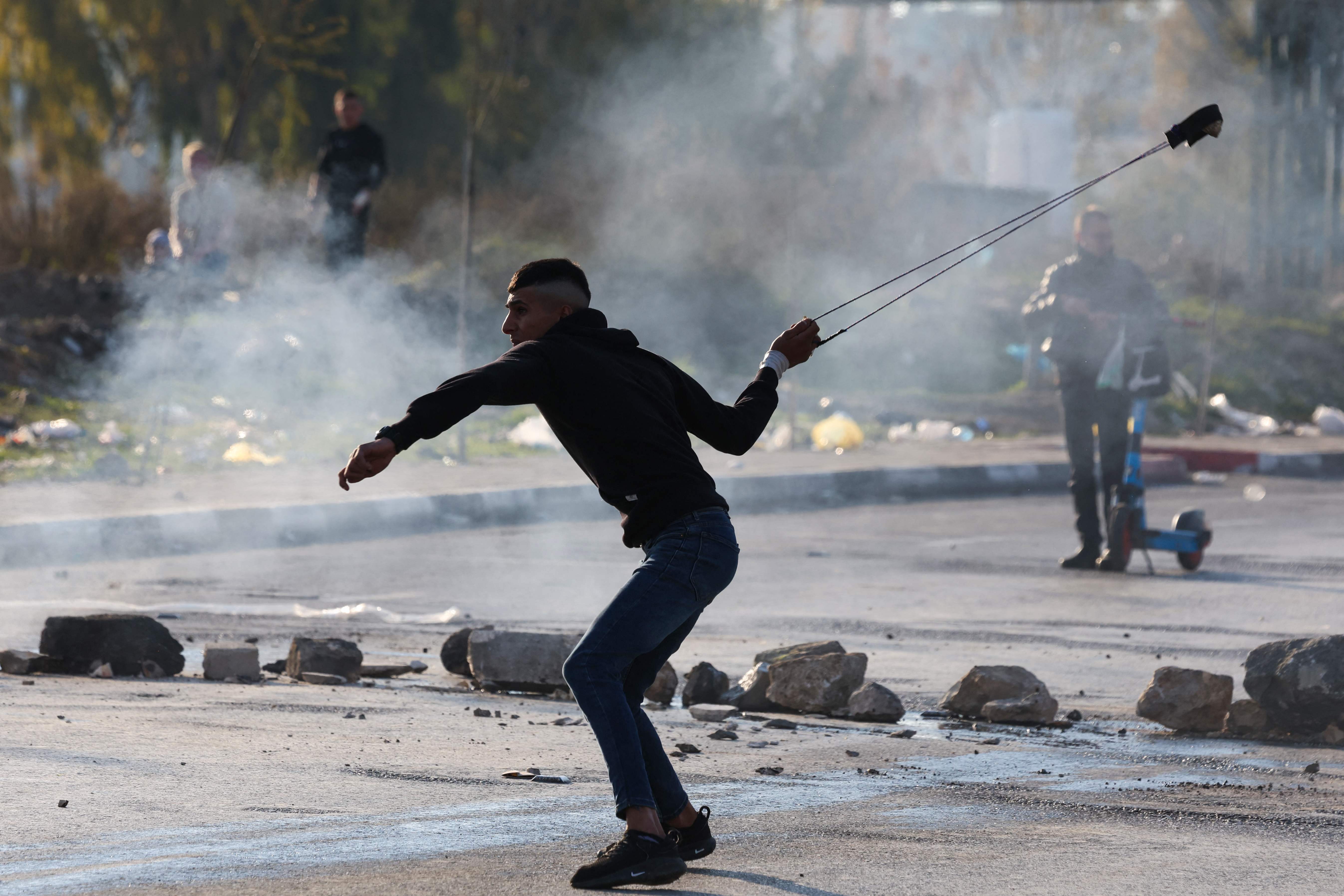 A Palestinian protester hurls a stone at Israeli forces at the northern entrance to Ramallah