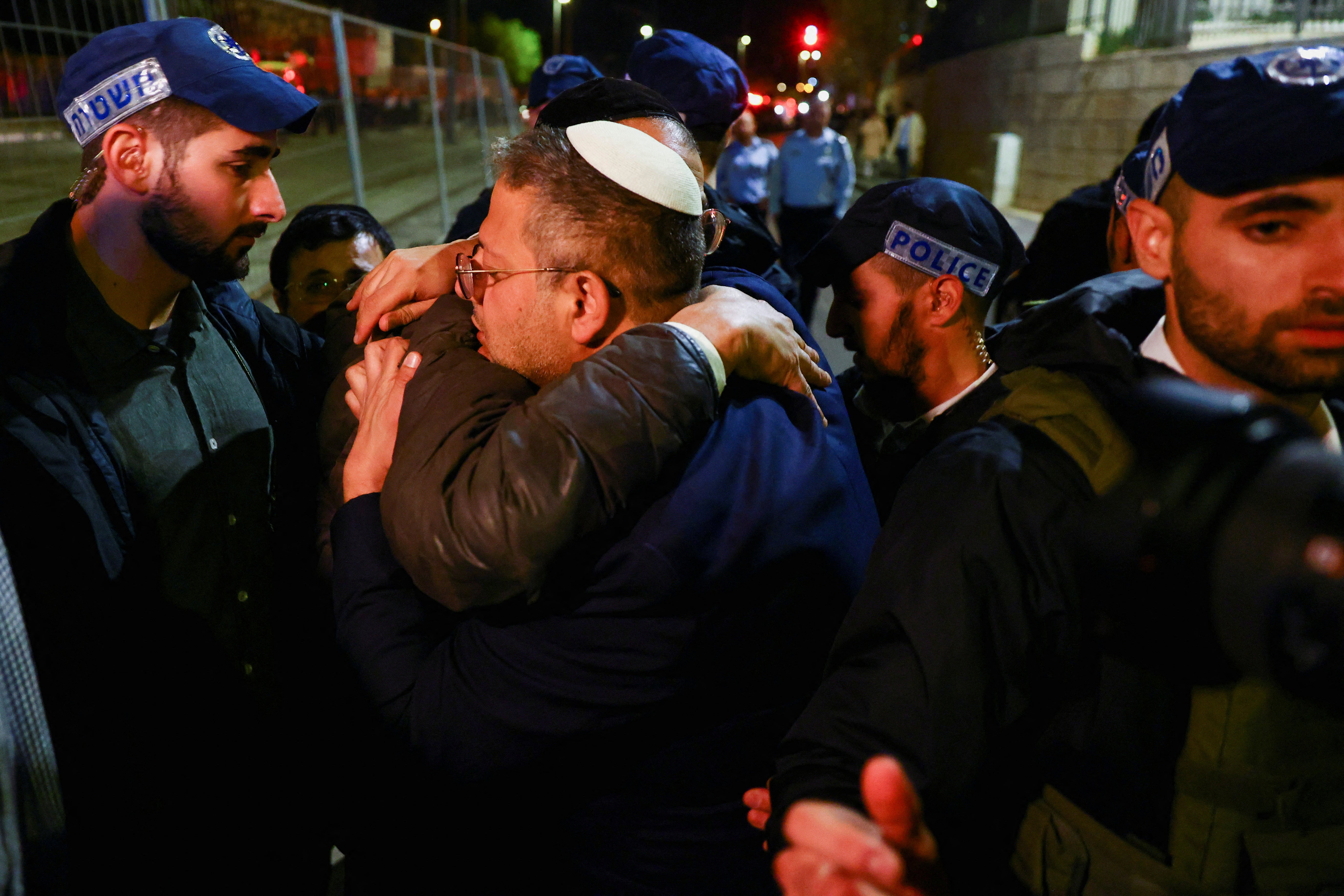 National security minister Itamar Ben-Gvir embraces a person while surrounded by Israeli forces near the scene of the shooting on Friday