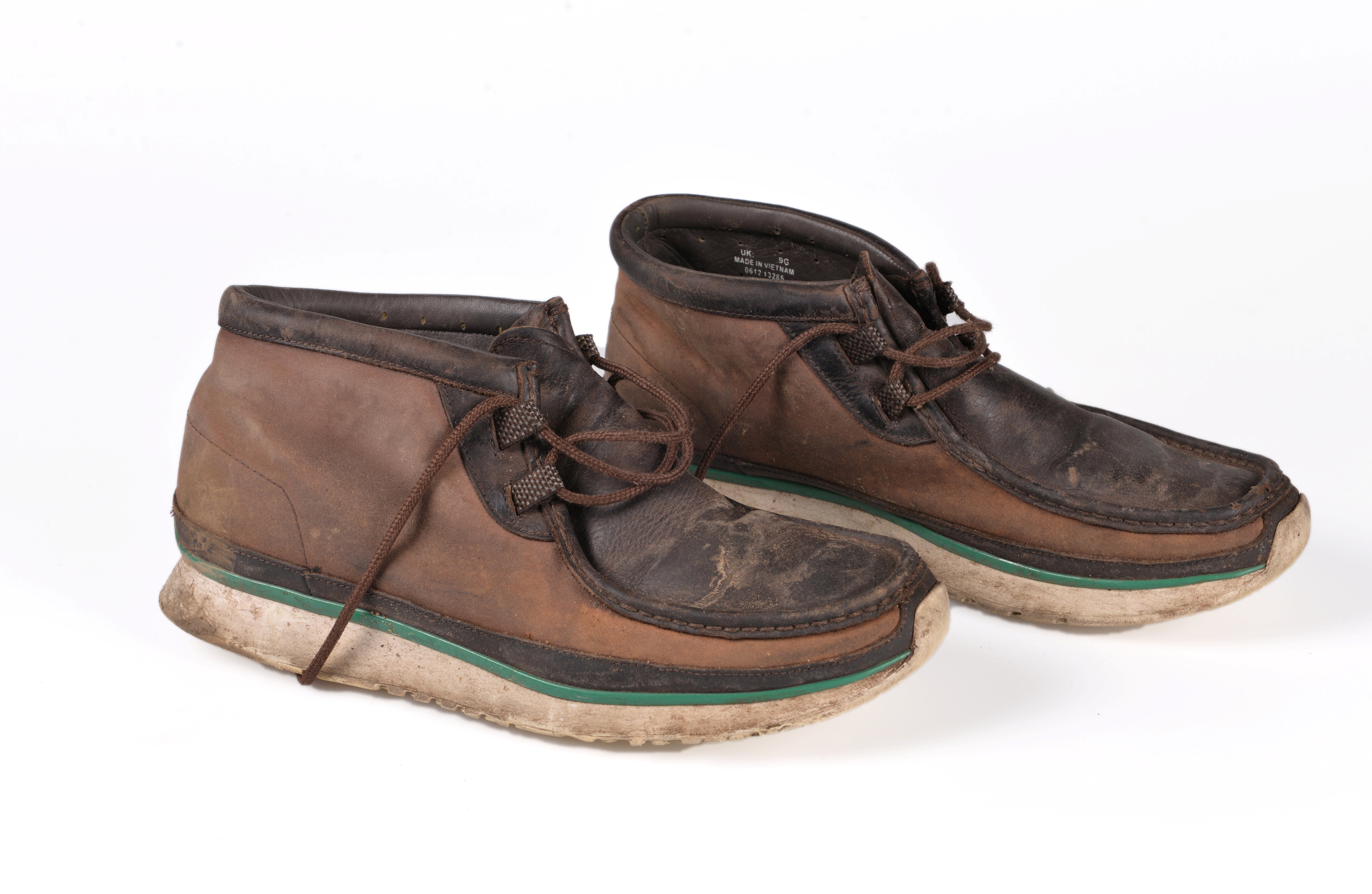 The man was wearing a beige jacket, beige trousers, a green and brown checked shirt, a blue diamond pattern jumper, brown shoes and a beige scarf and gloves