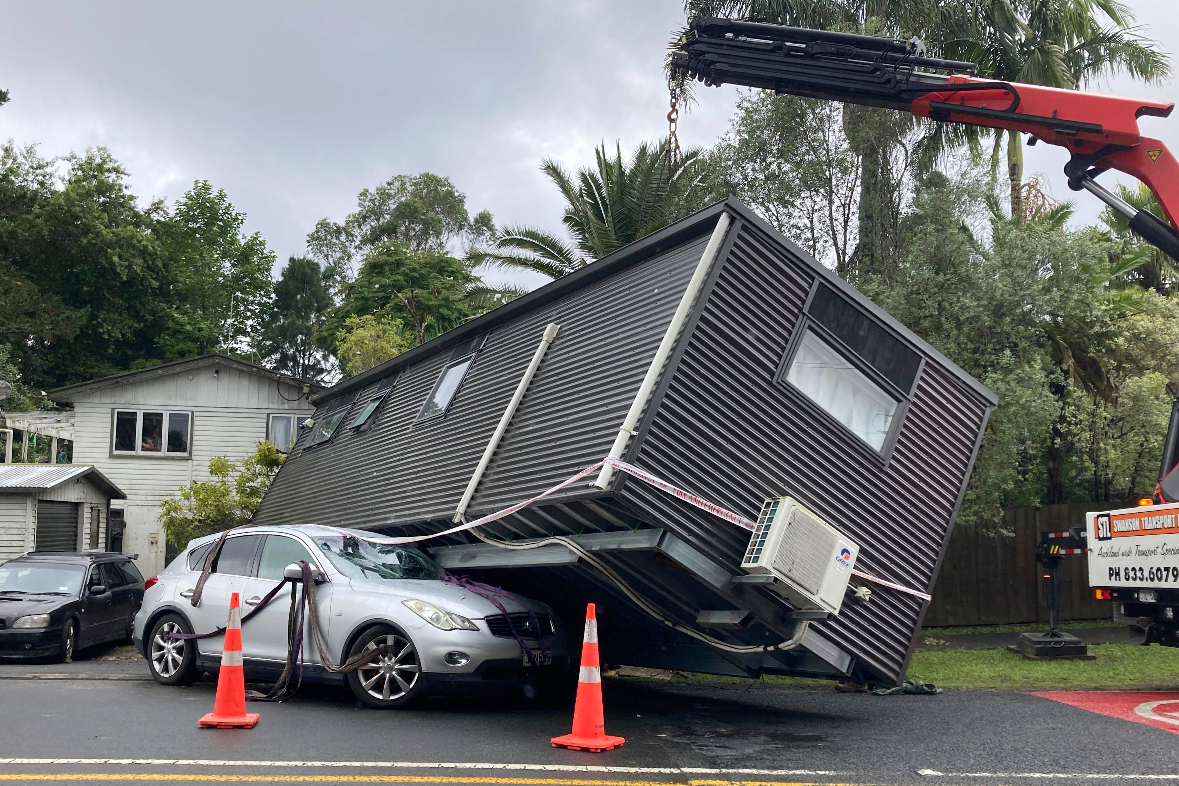 A portable building rests on a car after flood water shifted the structure in Auckland