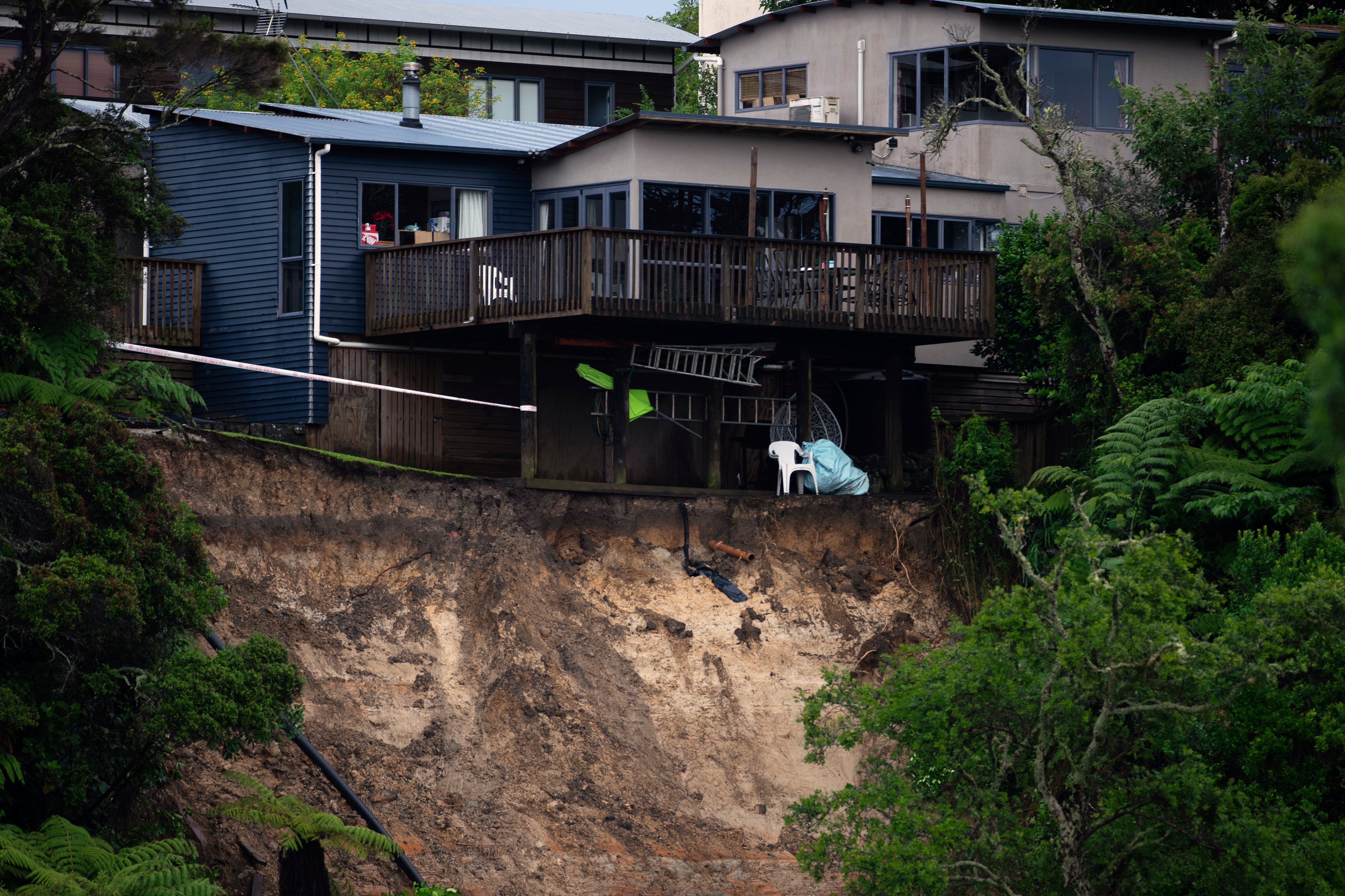 A landslip caused by flood water undermines a house in Auckland on Saturday after record rain fell on the city a day earlier