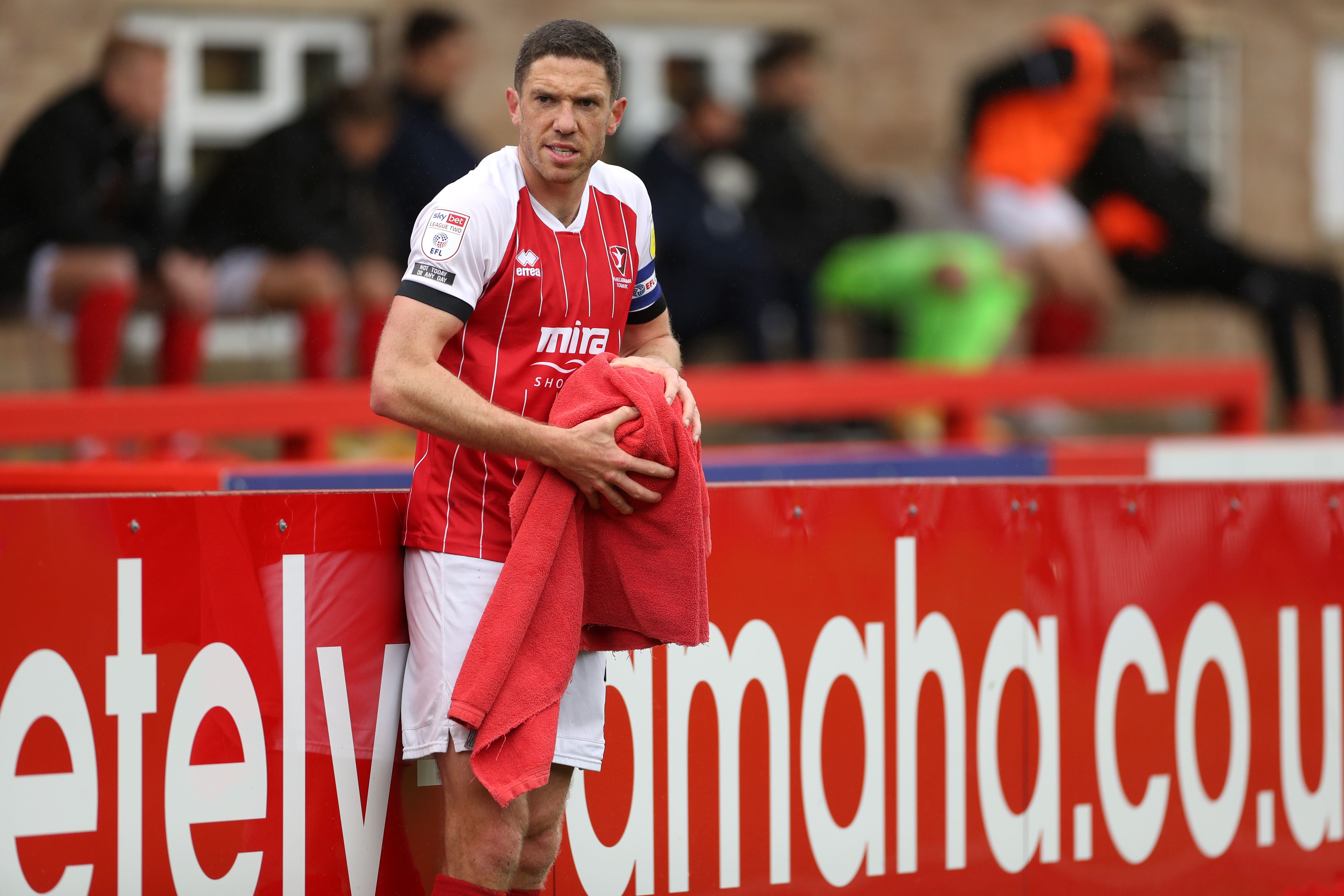 Ben Tozer dries the ball with a towel before taking a throw during his time with Cheltenham (Bradley Collyer/PA).