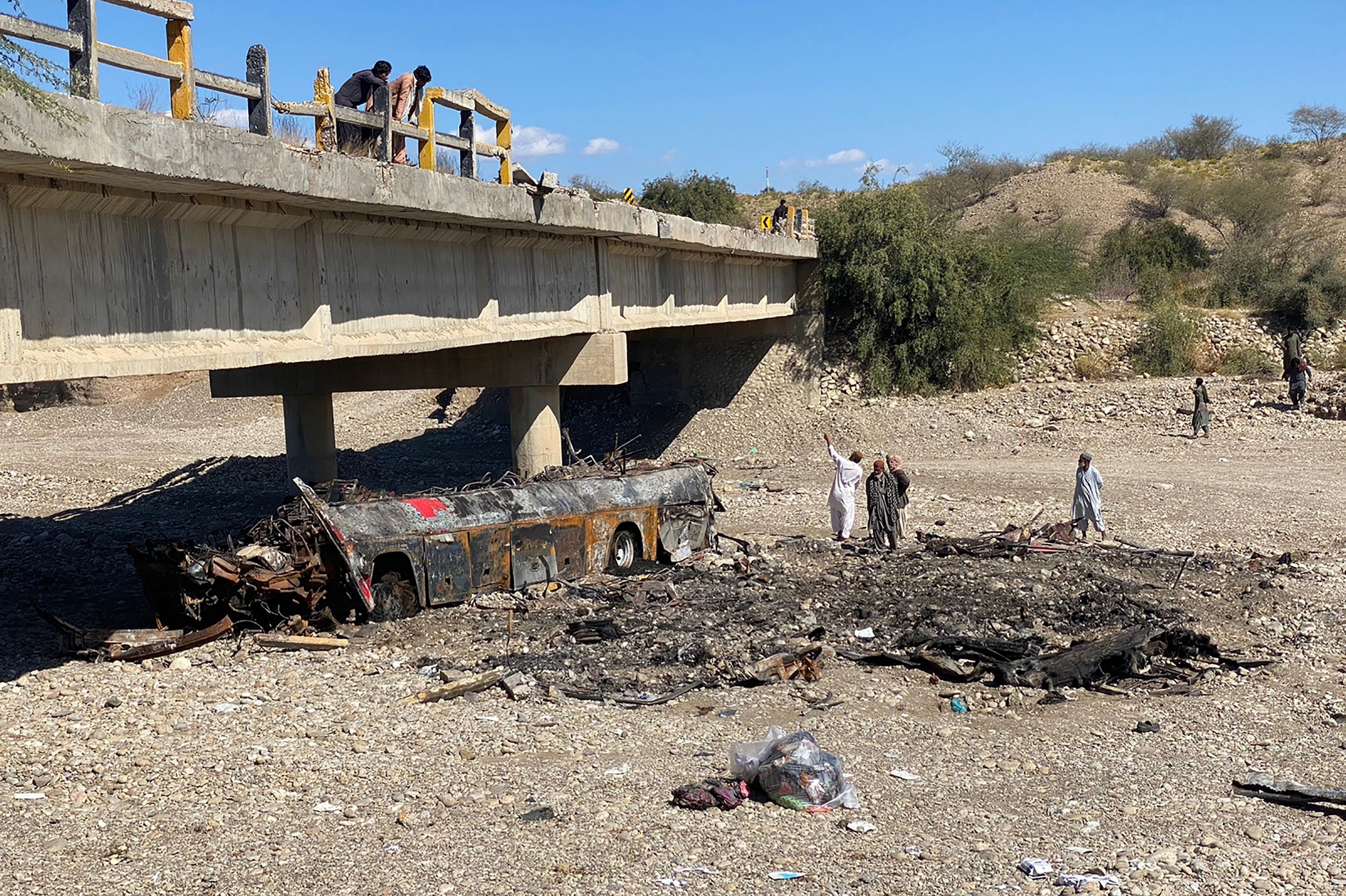 Residents look at the wreckage of a burnt passenger bus at Bela in Lasbela district of Pakistan’s Balochistan province