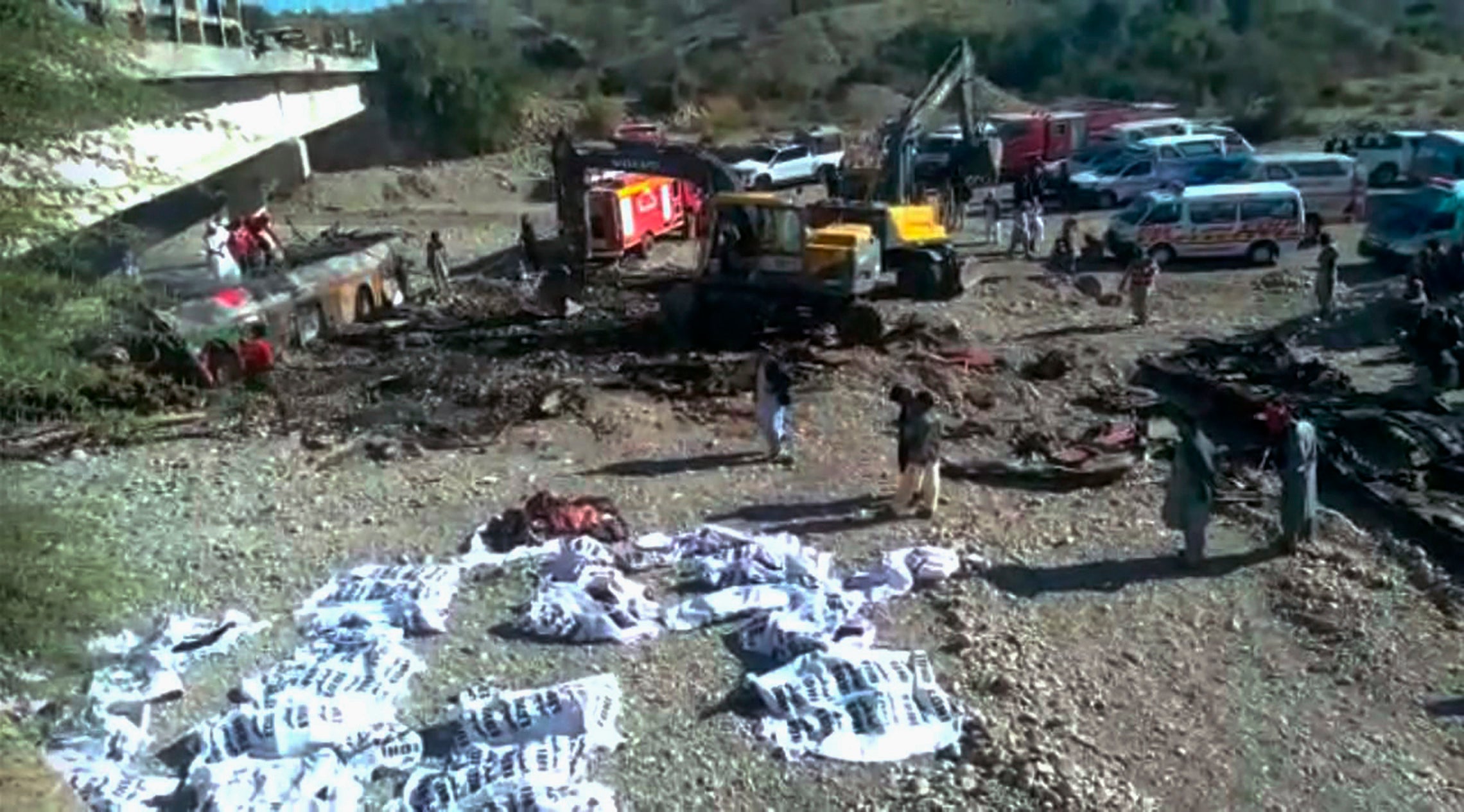 Rescue workers collect bodies from the burnt wreckage of a bus accident in Bela, an area of Lasbela district of Balochistan province