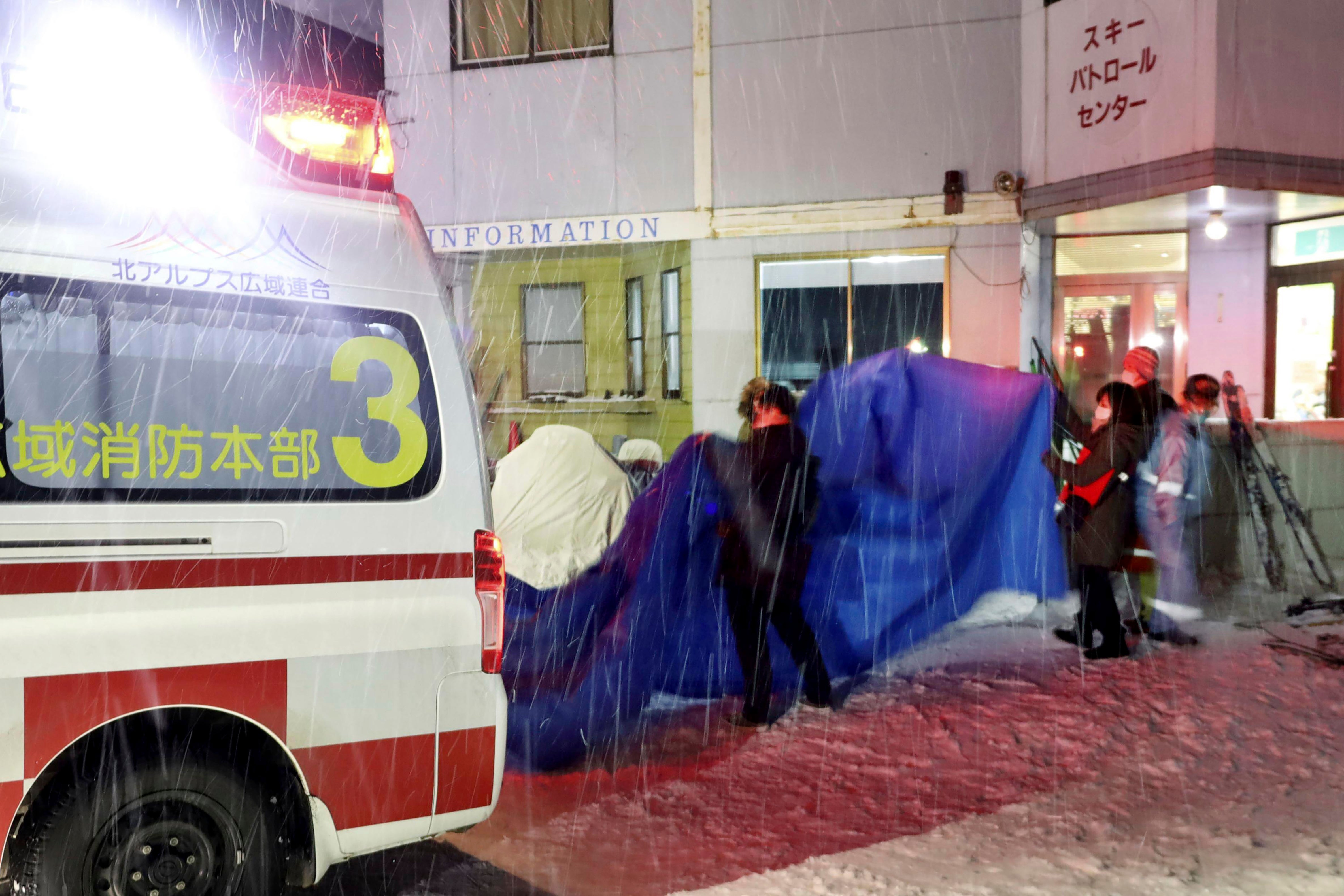 Injured skiers, behind a blue sheet, get into an ambulance at a ski resort in the village of Otari, Nagano prefecture, Japan Sunday, Jan. 29, 2023