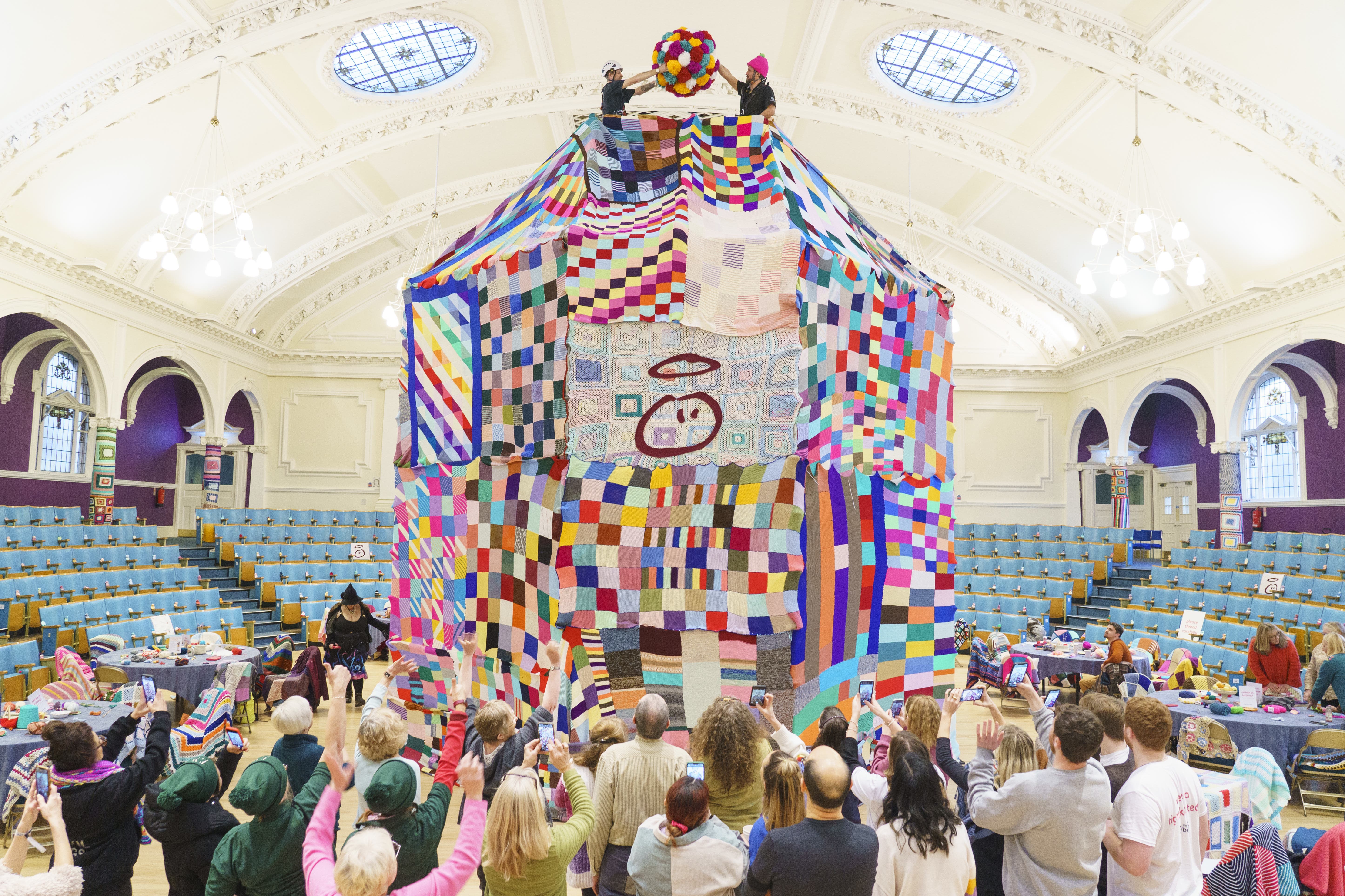 People watch as workers place a giant bobble on top of a 23ft high bobble hat (Dominic Lipinski/PA)