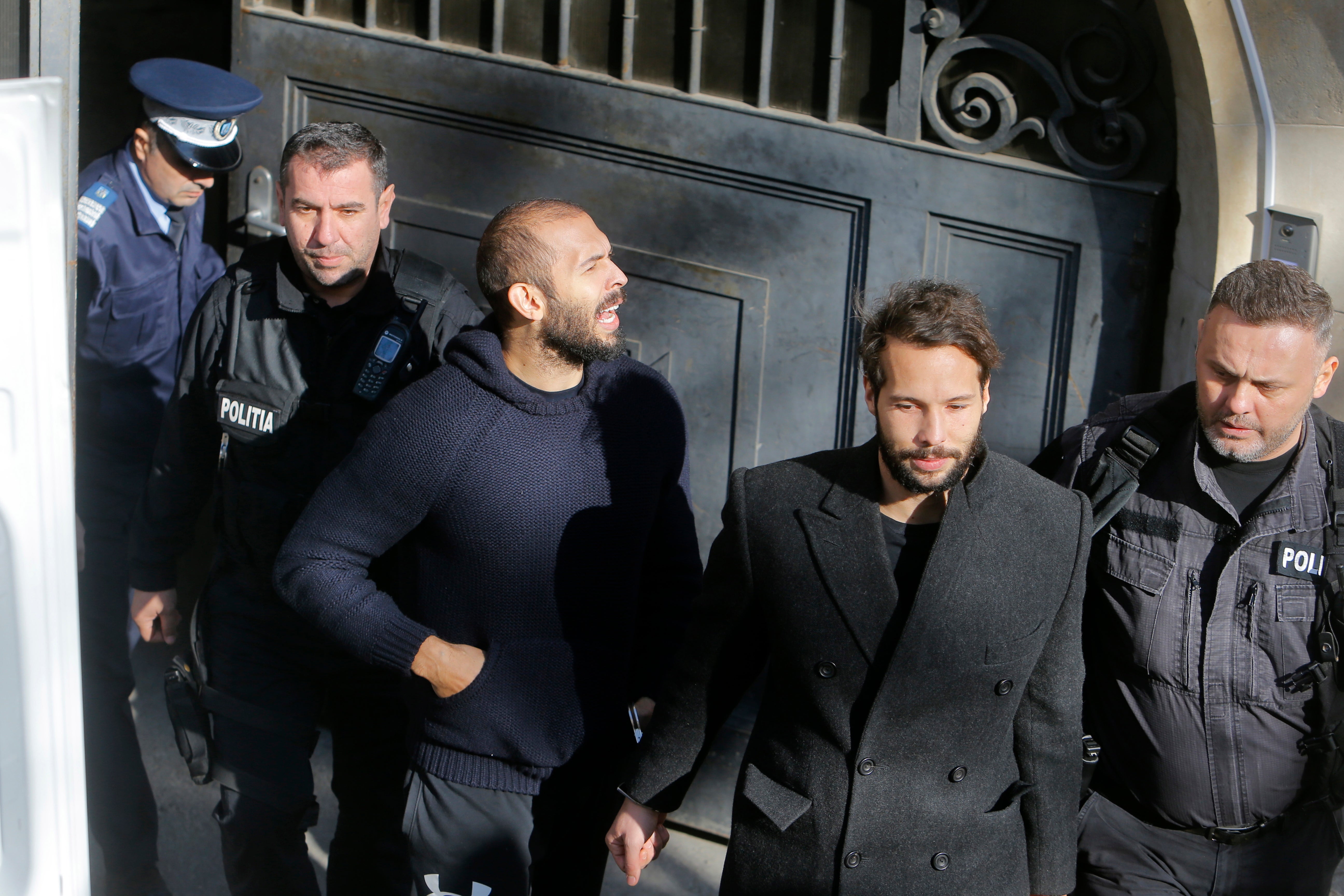 Andrew (centre) and Tristan (second from right) are escorted by police officers after a hearing at the Bucharest Court of Appeal