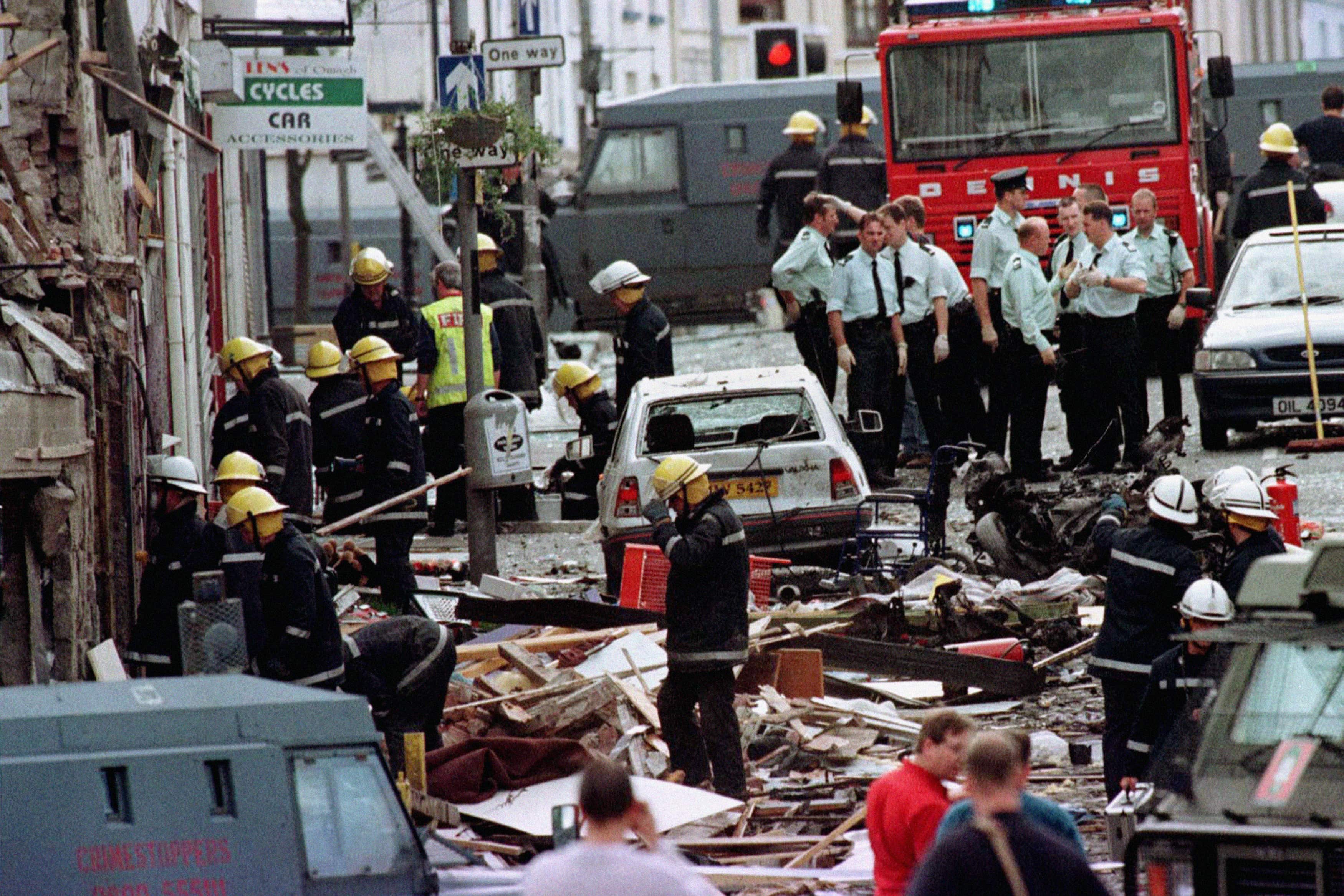 Police officers and firefighters inspect the damage caused by a bomb explosion in Market Street, Omagh (Paul McErlane/PA)