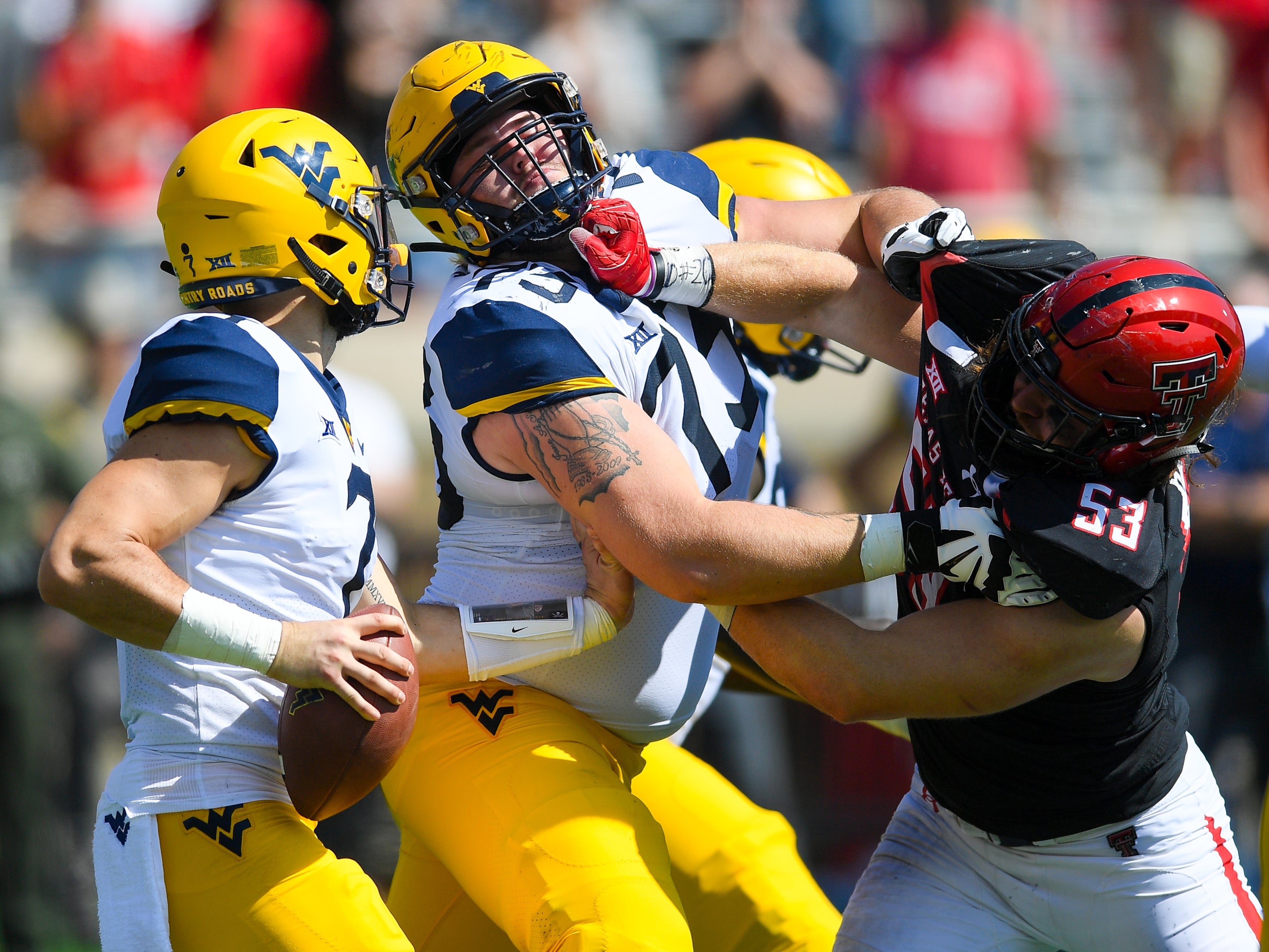 Eli Howard #53 of the Texas Tech Red Raiders fights through Josh Sills #73 while trying to get to Will Grier #7 of the West Virginia Mountaineers