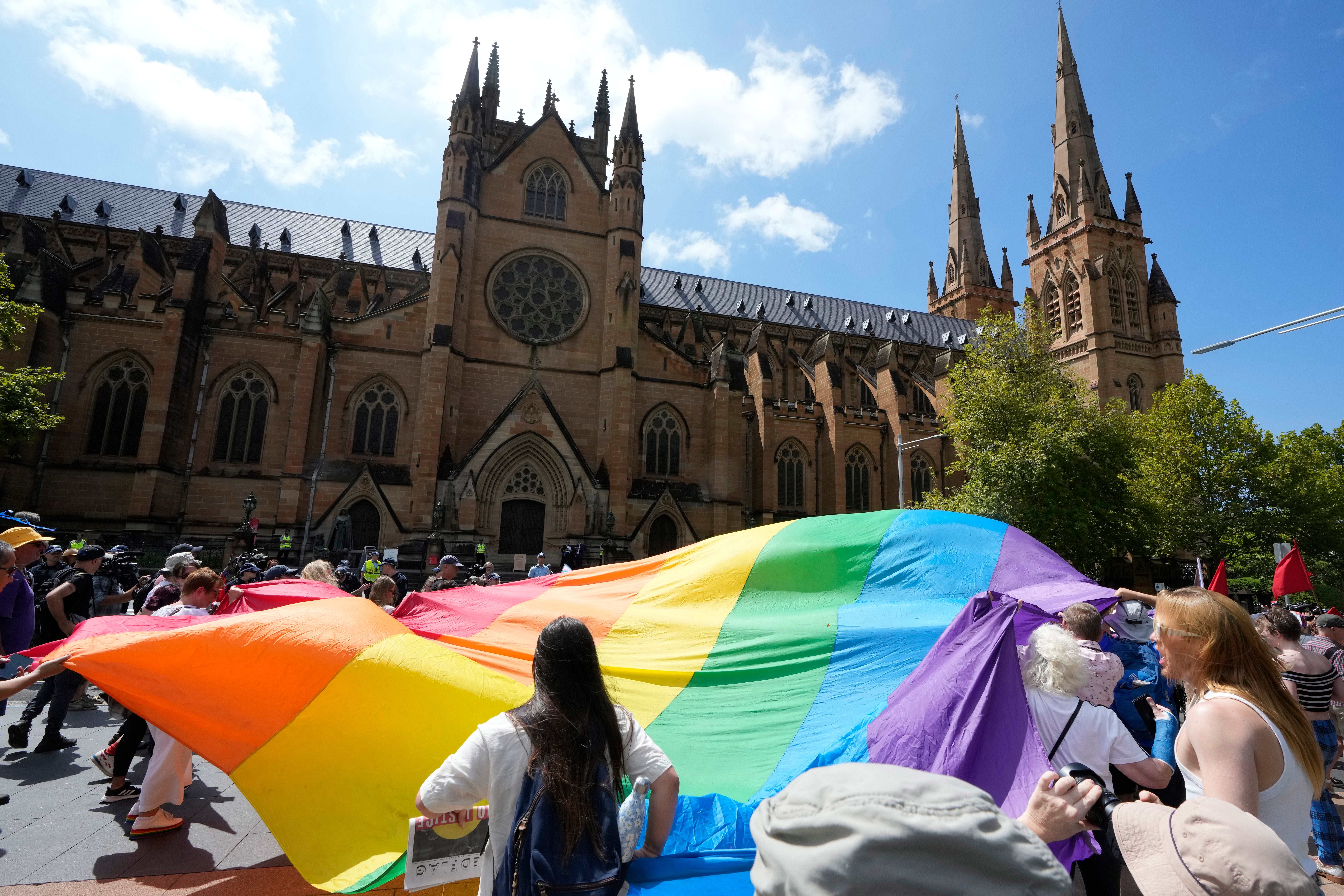Sydney-based gay rights group Community Action for Rainbow Rights carry a large rainbow flag at George Pell’s funeral. The conservative cardinal was known to refuse Communion to those wearing rainbow-coloured sashes