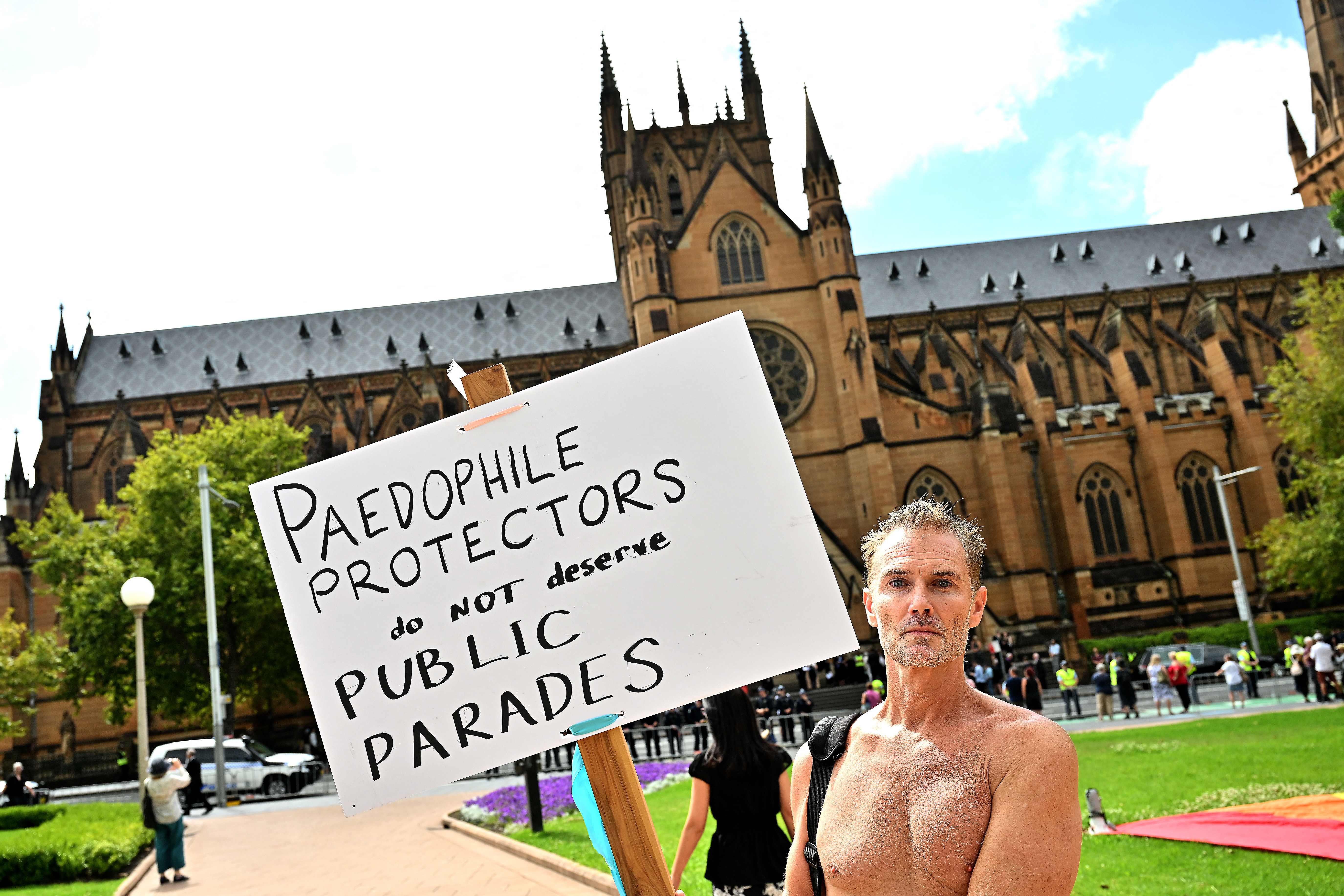 A protester holds a placard in front of St Mary’s Cathedral during the funeral of late Australian Catholic Cardinal George Pell in Sydney