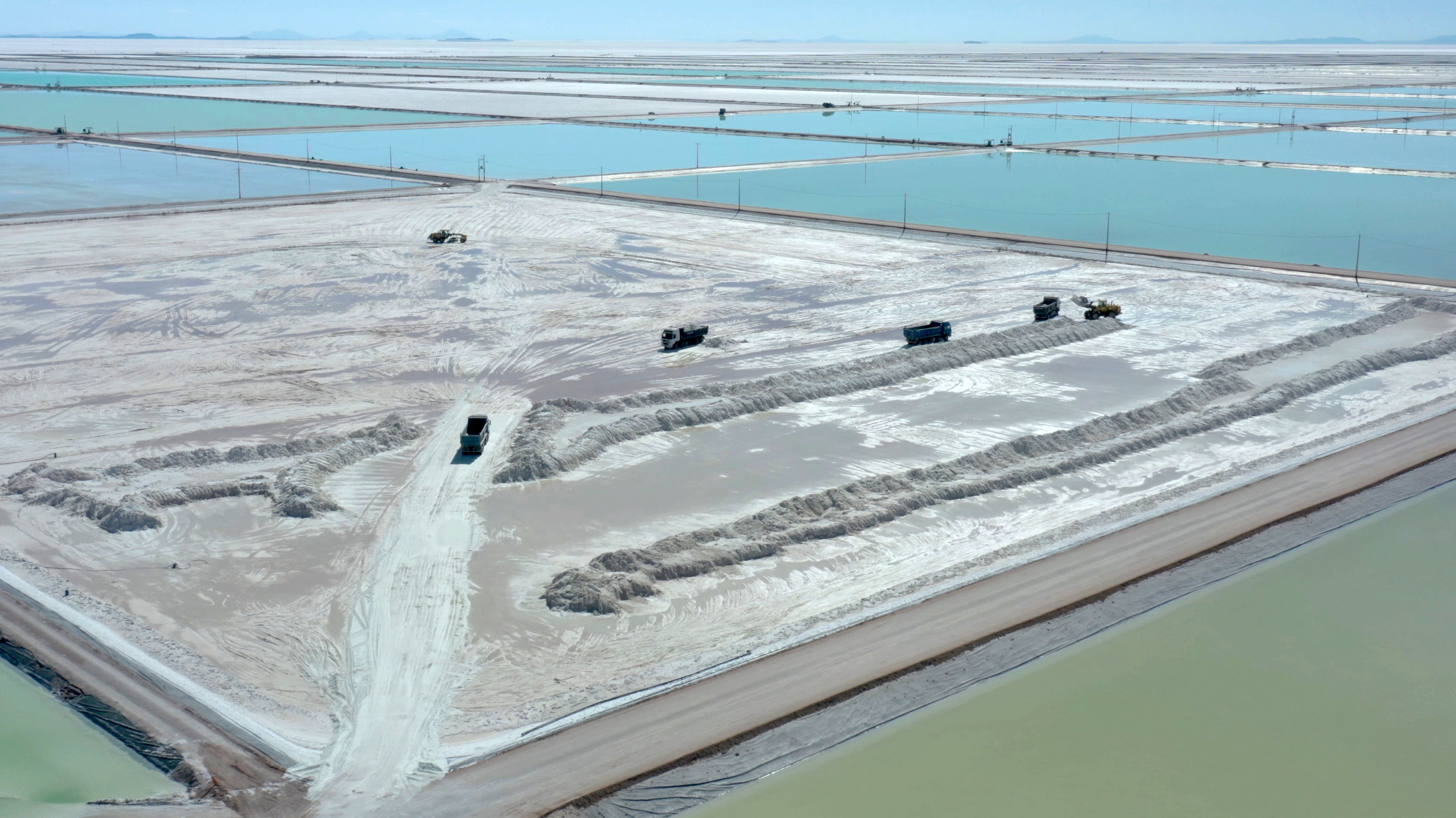 An aerial view of trucks loading brine from the evaporation pools of a state-owned lithium extraction complex in Bolivia