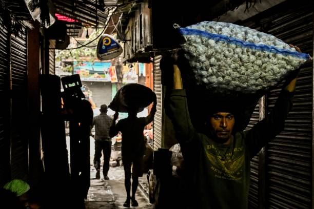 A worker carries a sack of garlic as he crosses an alley