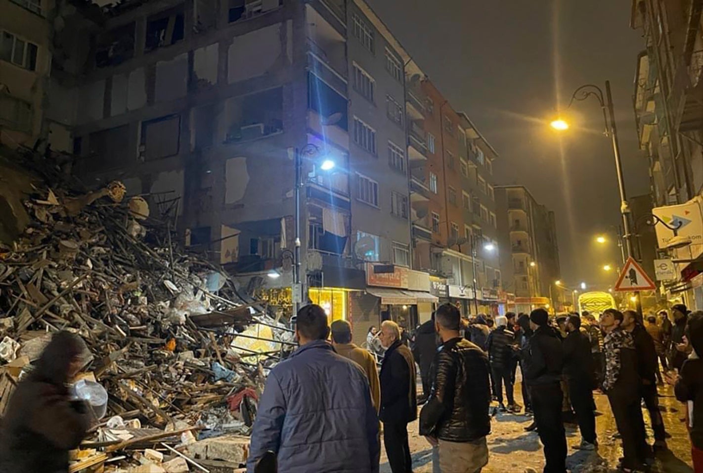 People gather around a collapsed building in Pazarcik, in Kahramanmaras province