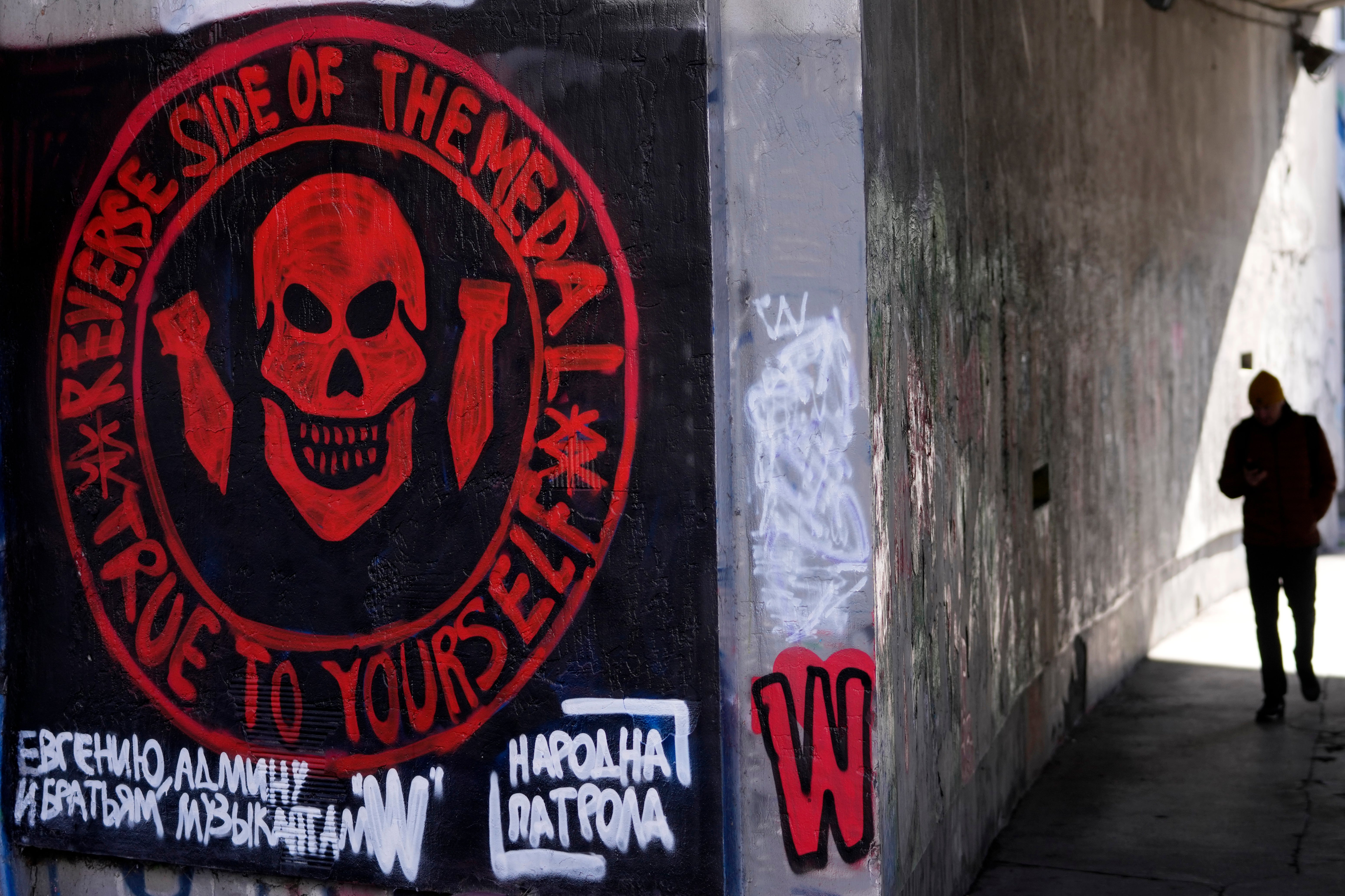 A man walks by a drawn again mural depicting the logo of Russia's Wagner Group on a wall in Belgrade, Serbia