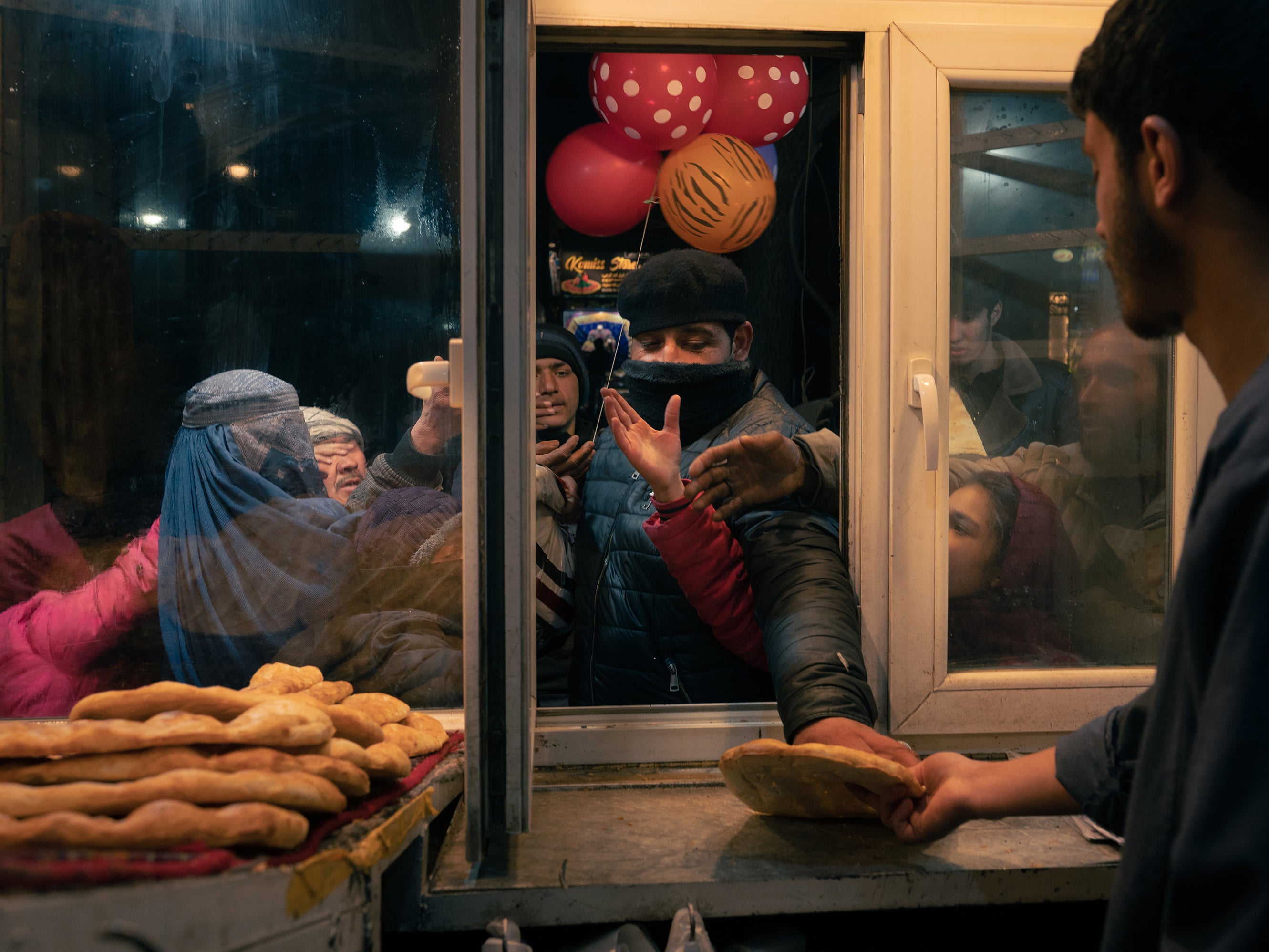 A customer buys bread at a Kabul bakery to give to desperate Afghans