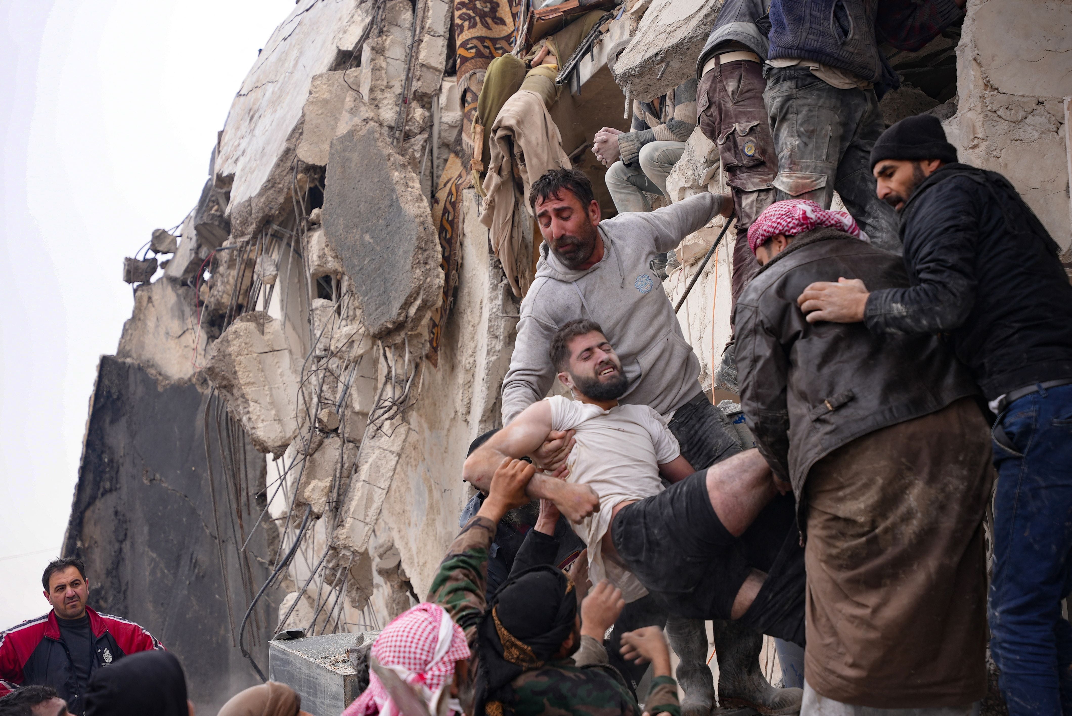 Residents retrieve an injured man from the rubble of a collapsed building following an earthquake in the town of Jandaris, in the countryside of Syria's northwestern city of Afrin in the opposition-held part of Aleppo province