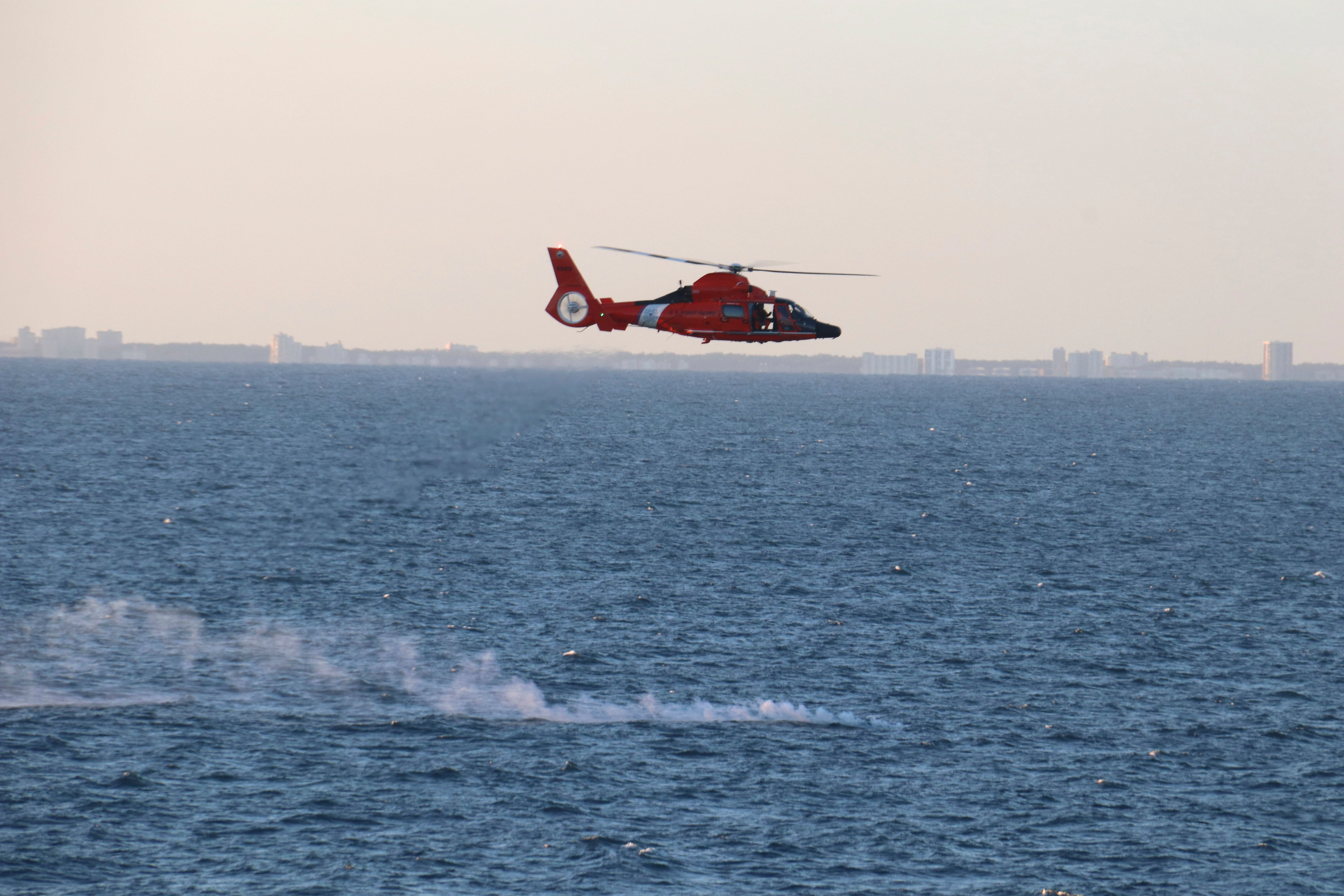 In this image provided by the US Navy, a US Coast Guard helicopter flies over a debris field during recovery efforts of a high-altitude surveillance balloon on 4 February