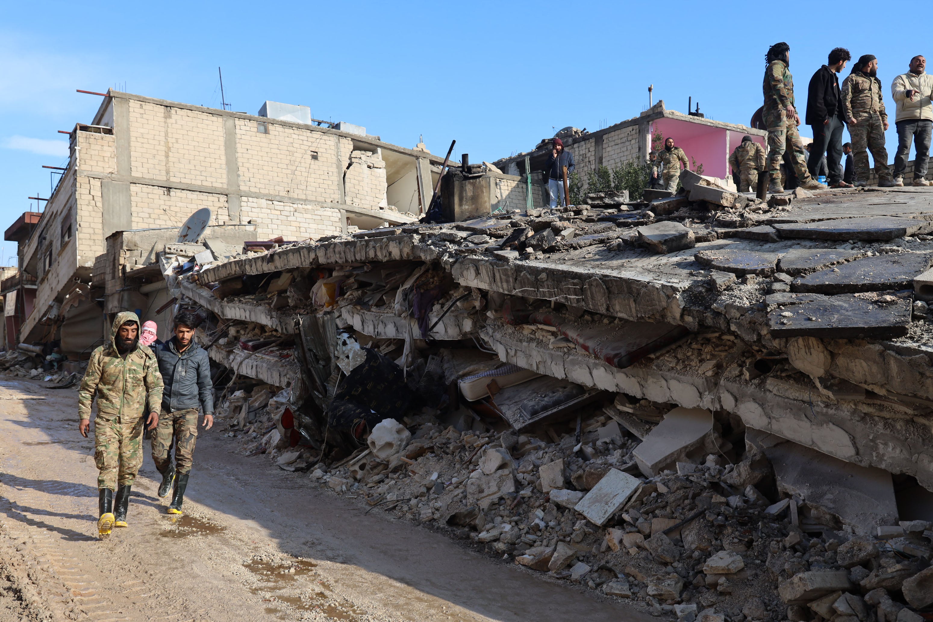 Syrian rescuers gather above the rubble of a collapsed building, on February 7, 2023, in the town of Jandaris, in the rebel-held part of Aleppo province, as a search operation continues following a deadly earthquake