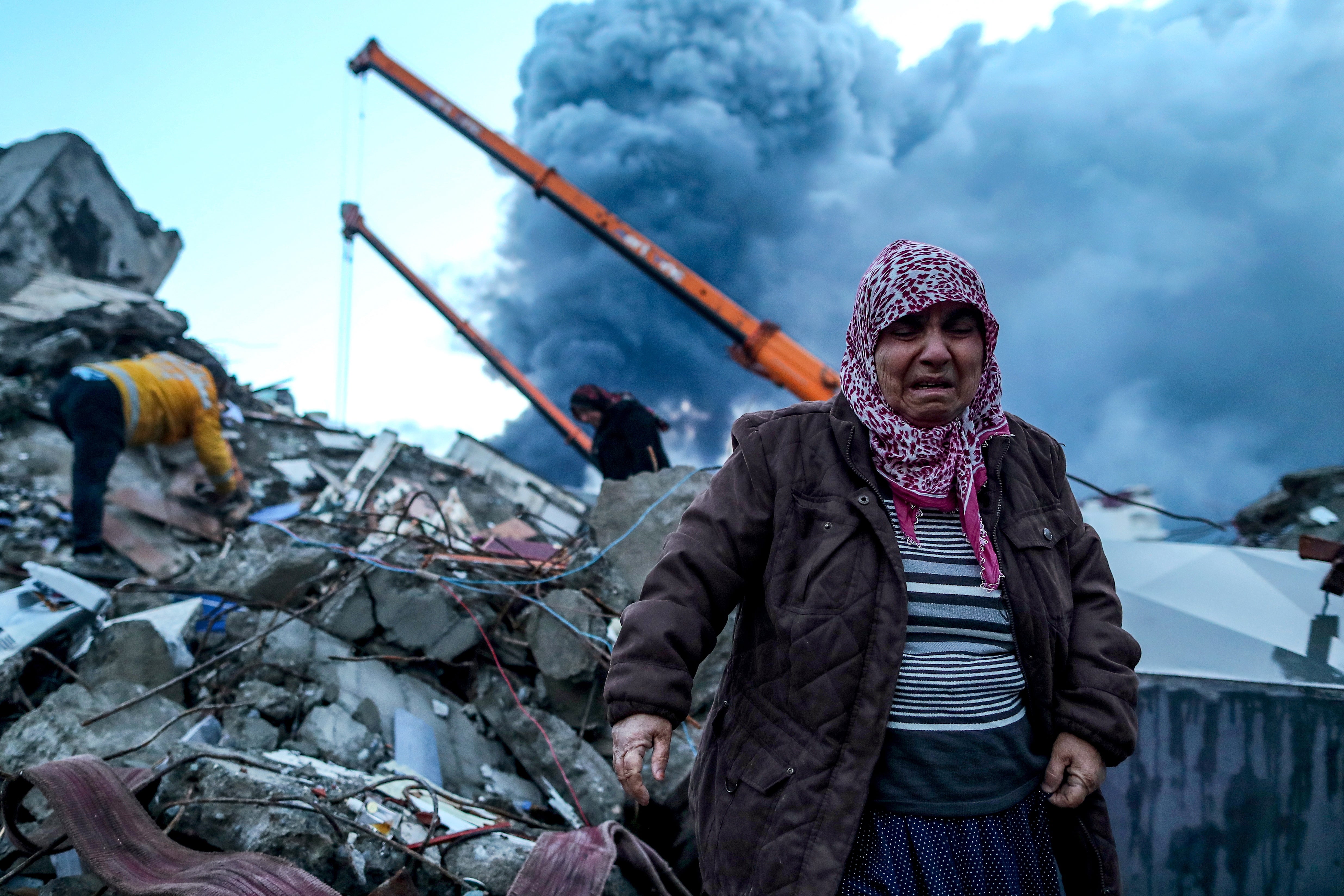 A woman reacts as emergency personnel search for victims at the site of a collapsed building after an earthquake in Iskenderun