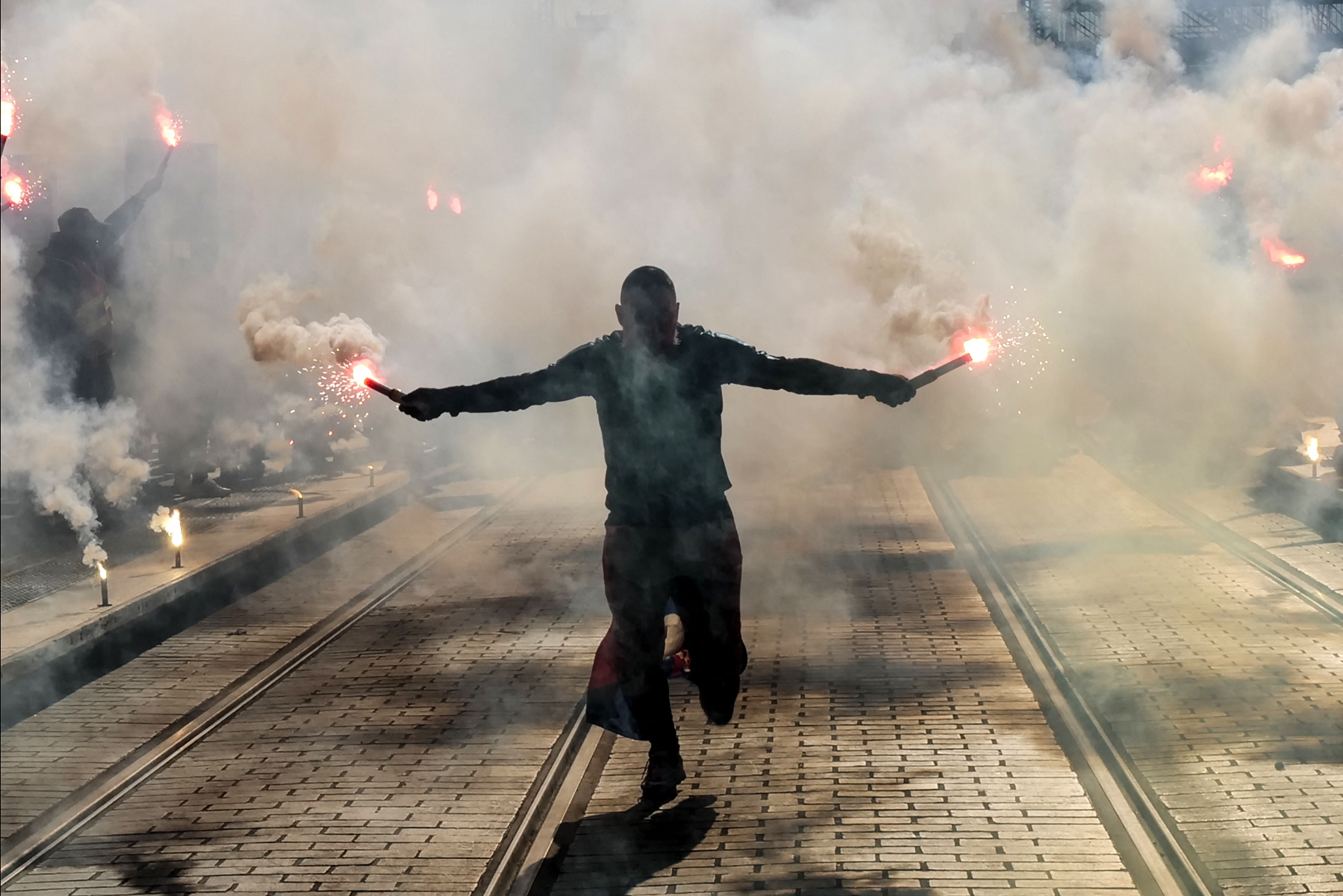 A protester holds burning flares during a demonstration on the third day of nationwide rallies and strikes against a pensions reform plan in Nice, France