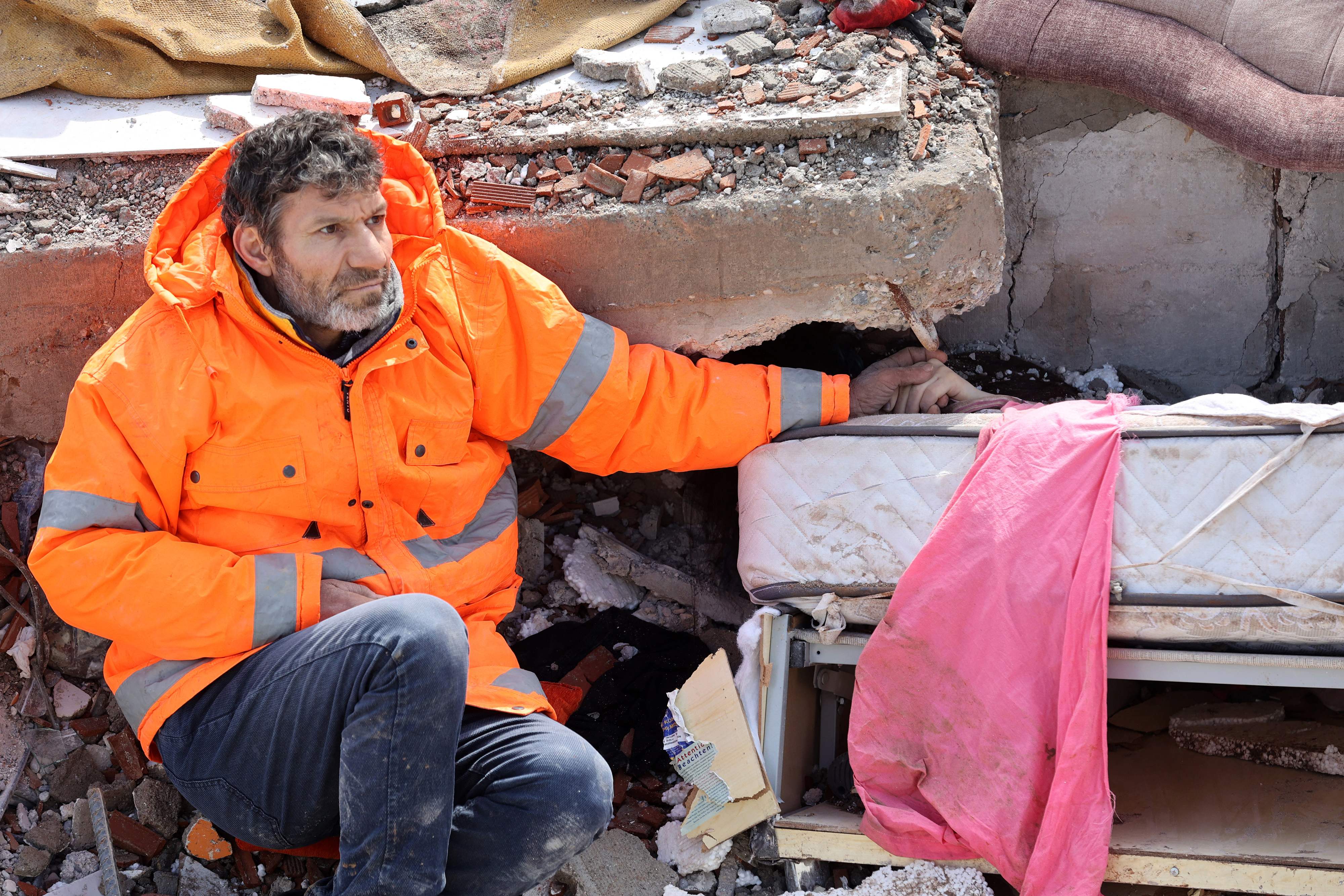 Mesut Hancer holds the hand of his 15-year-old daughter Irmak, who died in the earthquake in Kahramanmaras, close to the quake's epicentre