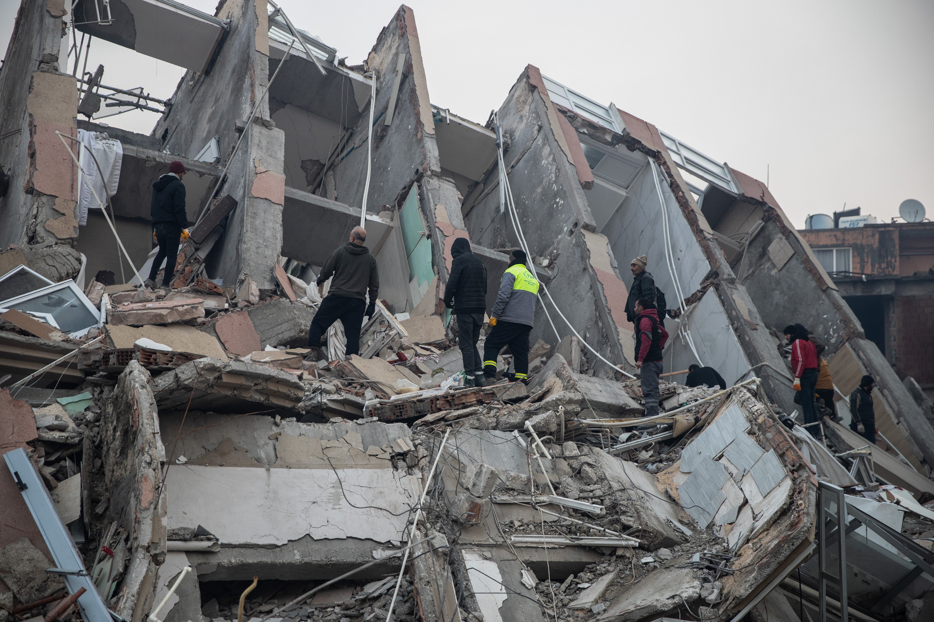 People try to rescue their loved ones, believed to be trapped under collapsed building, in Iskenderun, Turkey