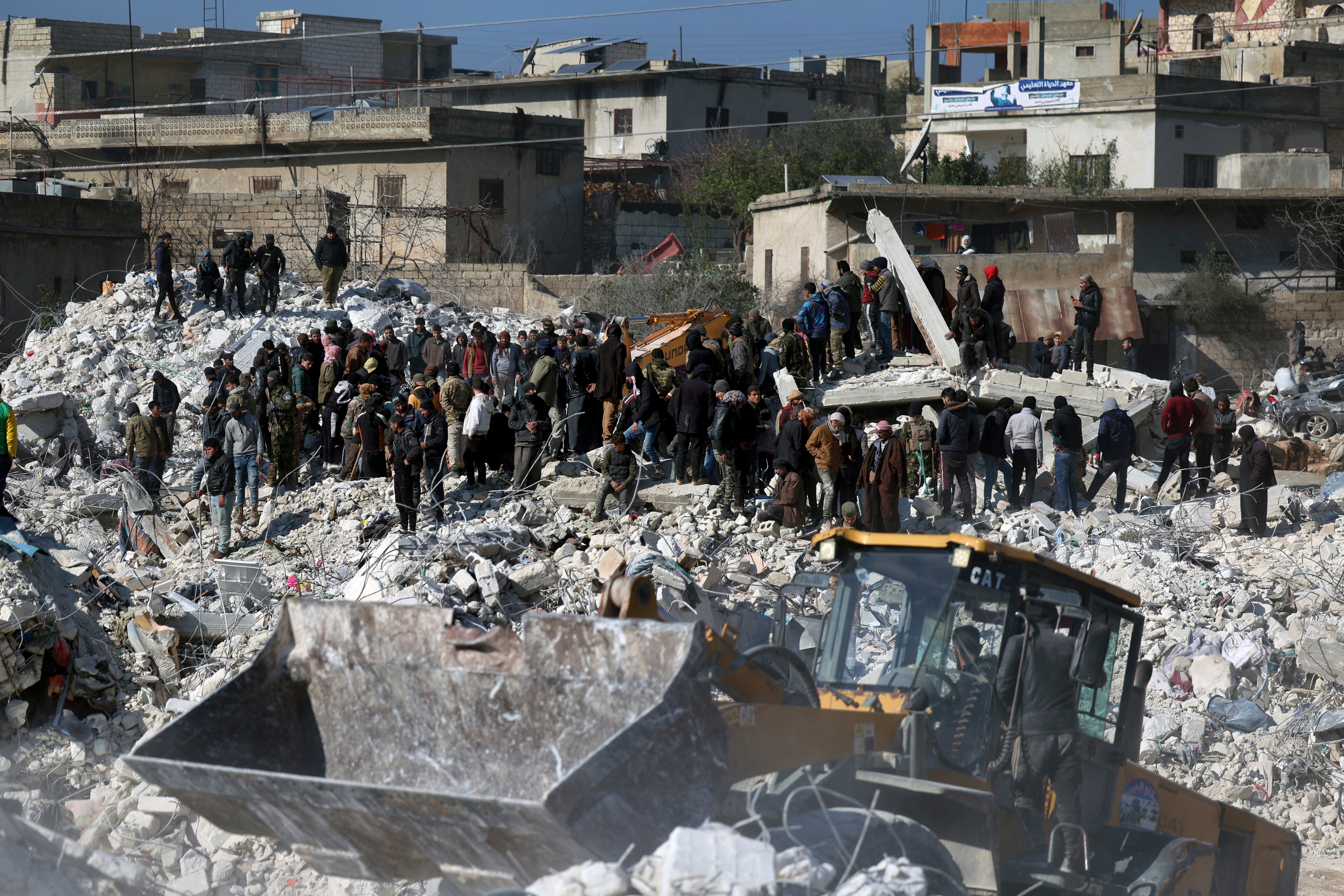 Rescuers and residents search through the rubble of collapsed buildings in the town of Harem near the Turkish border, Idlib province, Syria