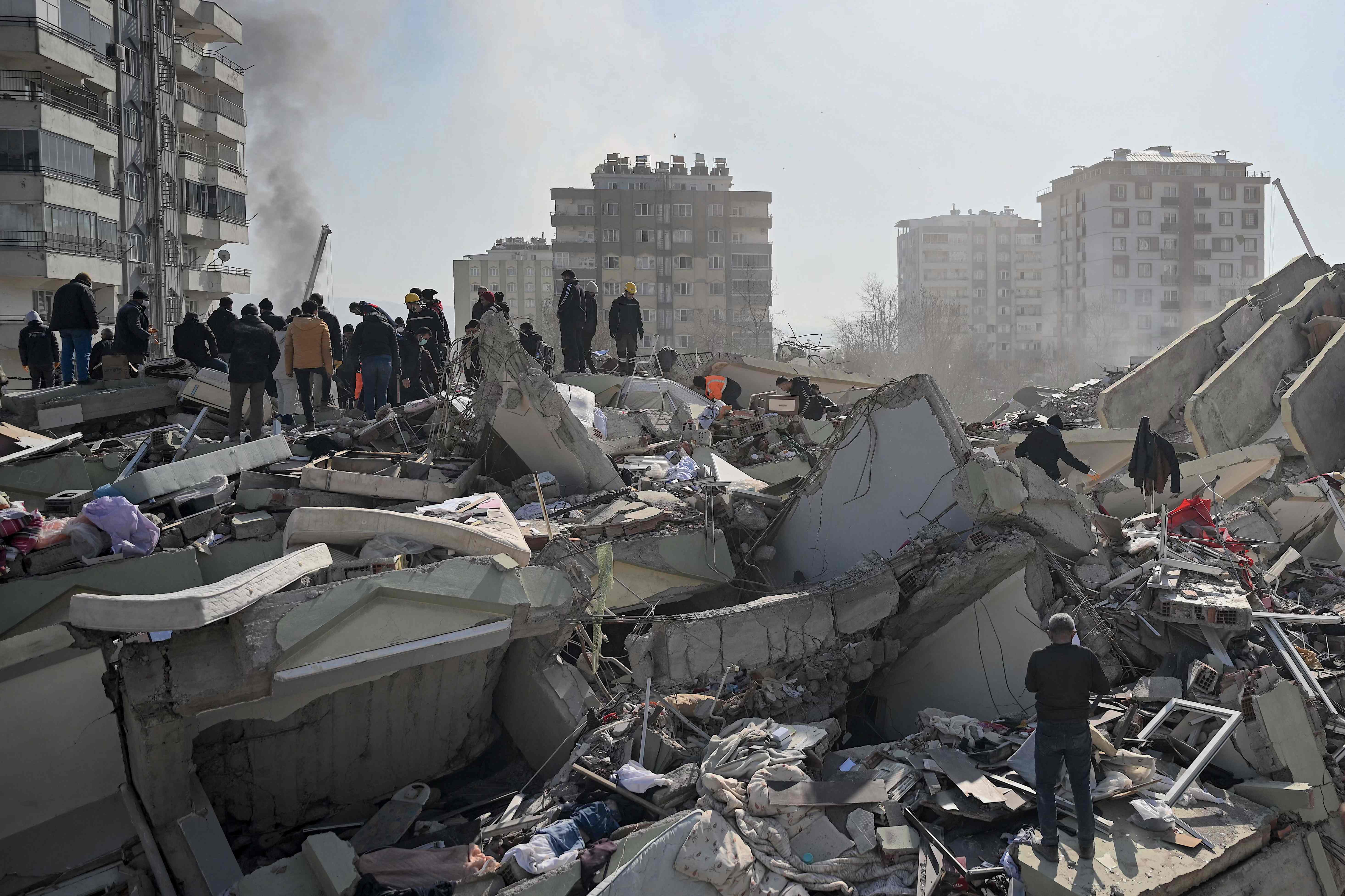 People wait as rescuers search for victims and survivors among the rubble of collapsed buildings in Kahramanmaras, on February 9, 2023, three days after a 7,8-magnitude earthquake struck southeast Turkey