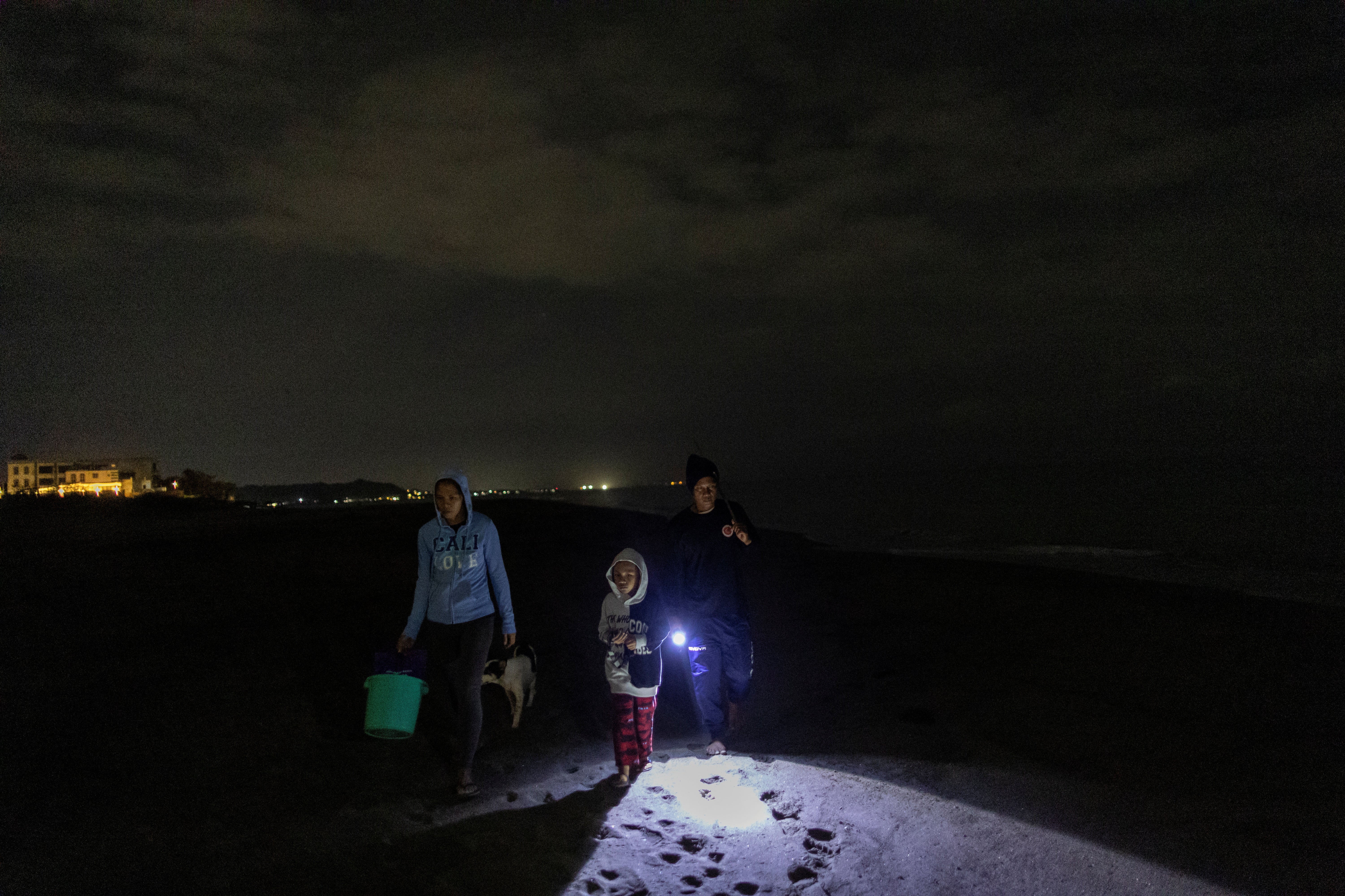 Cabagbag, his son Gabriel, 7, his wife Jonnibel, 39, and their two dogs look for turtle tracks and nests in the sand