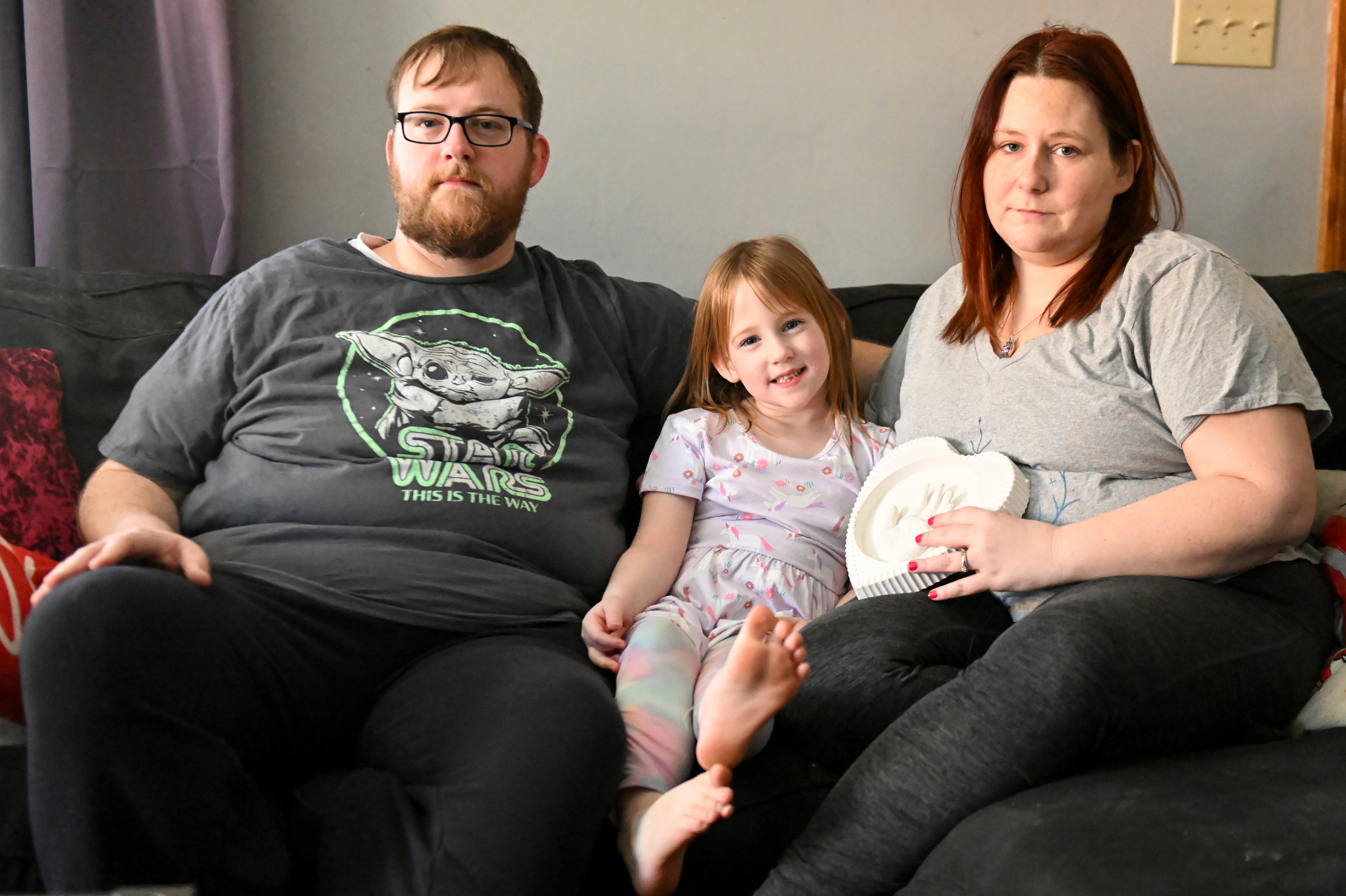 Andrew Weaver, from left, Caitlin Weaver and Jessica Day-Weaver hold a ceramic hand print of daughter, Anastasia, at their home, Thursday, Feb. 2, 2022, in Boardman, Ohio