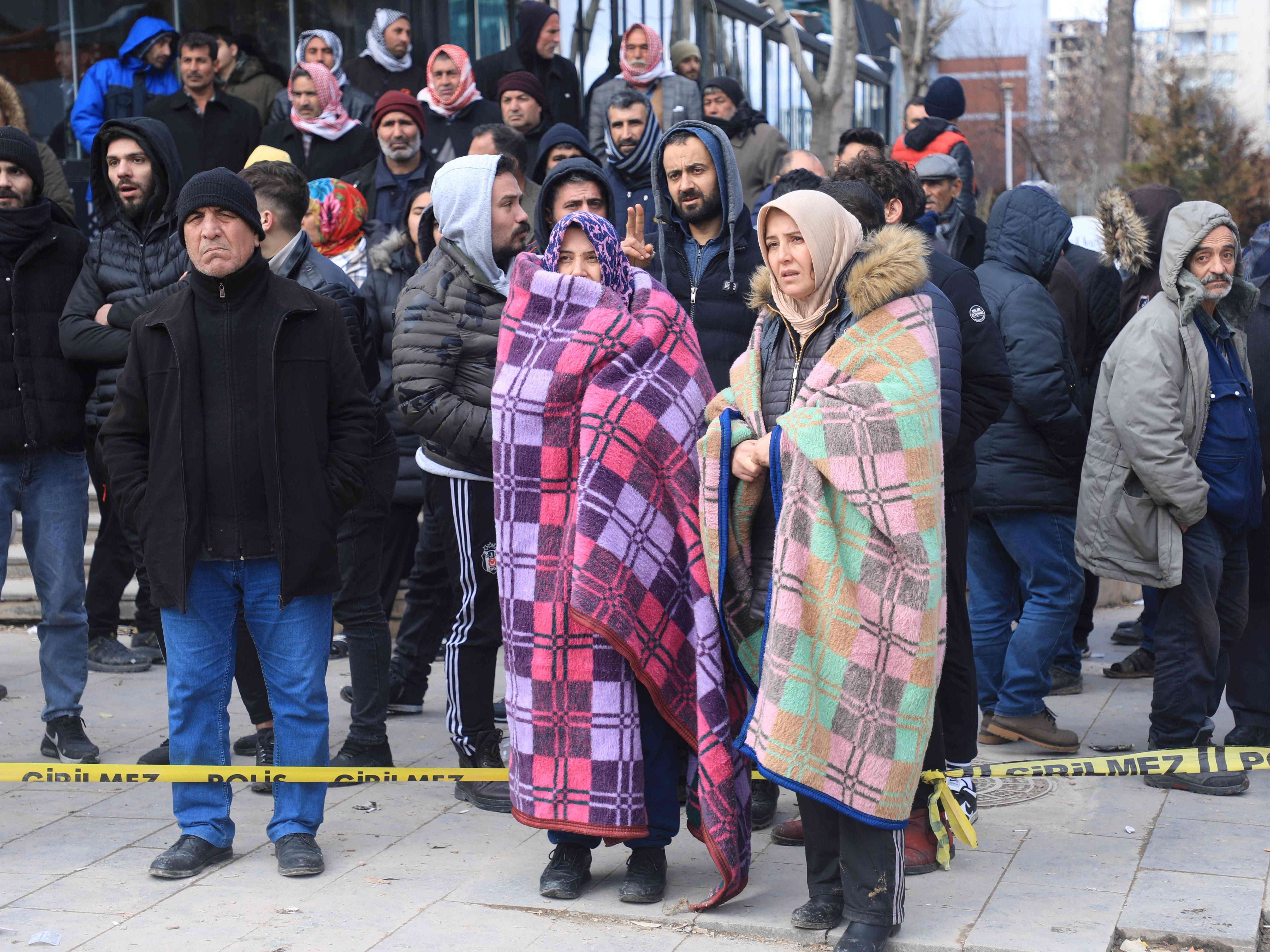 People watch rescuers search for victims and survivors in the rubble