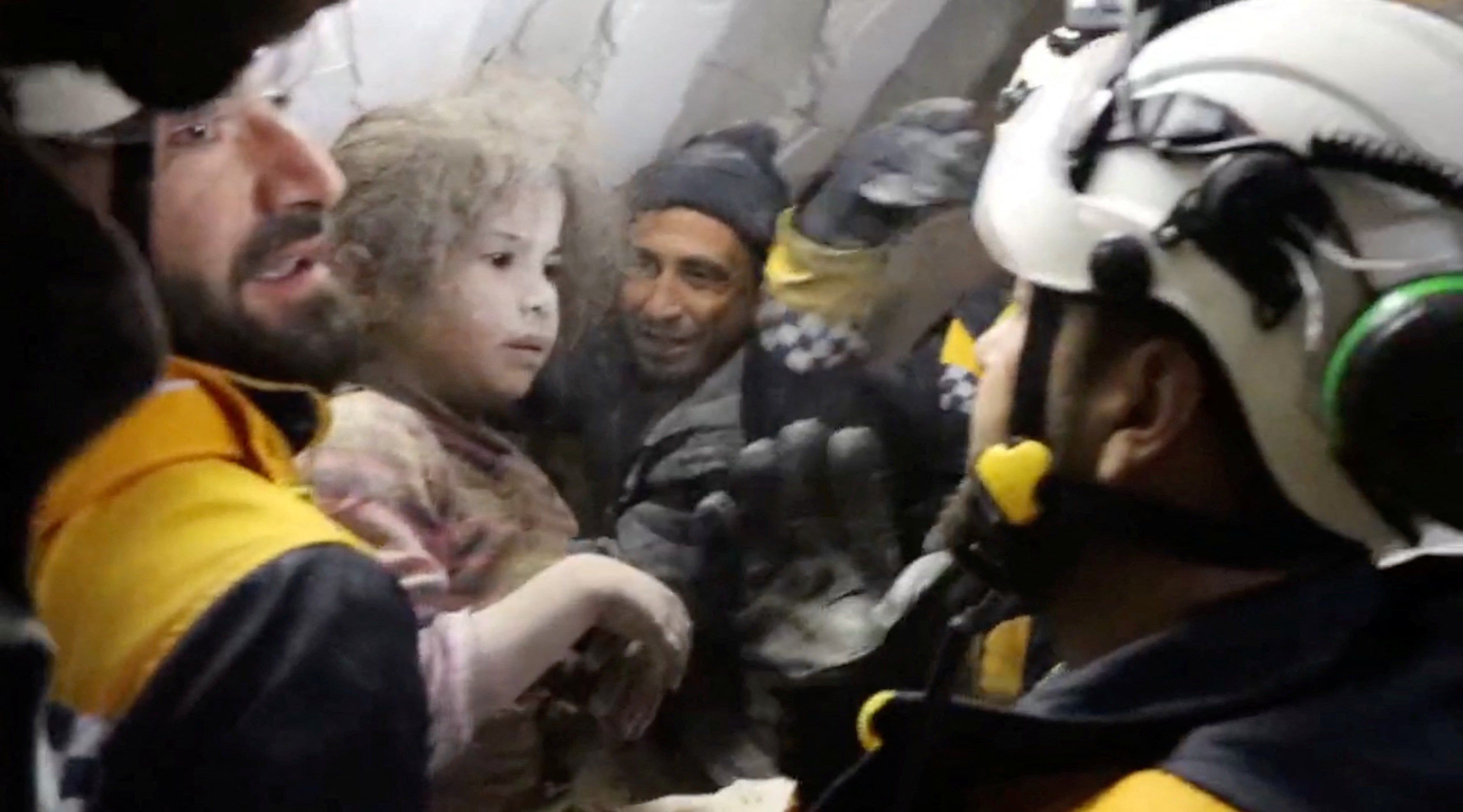 The White Helmet volunteers hold a child after pulling her out of the rubble in the aftermath of a deadly earthquake on 8 February