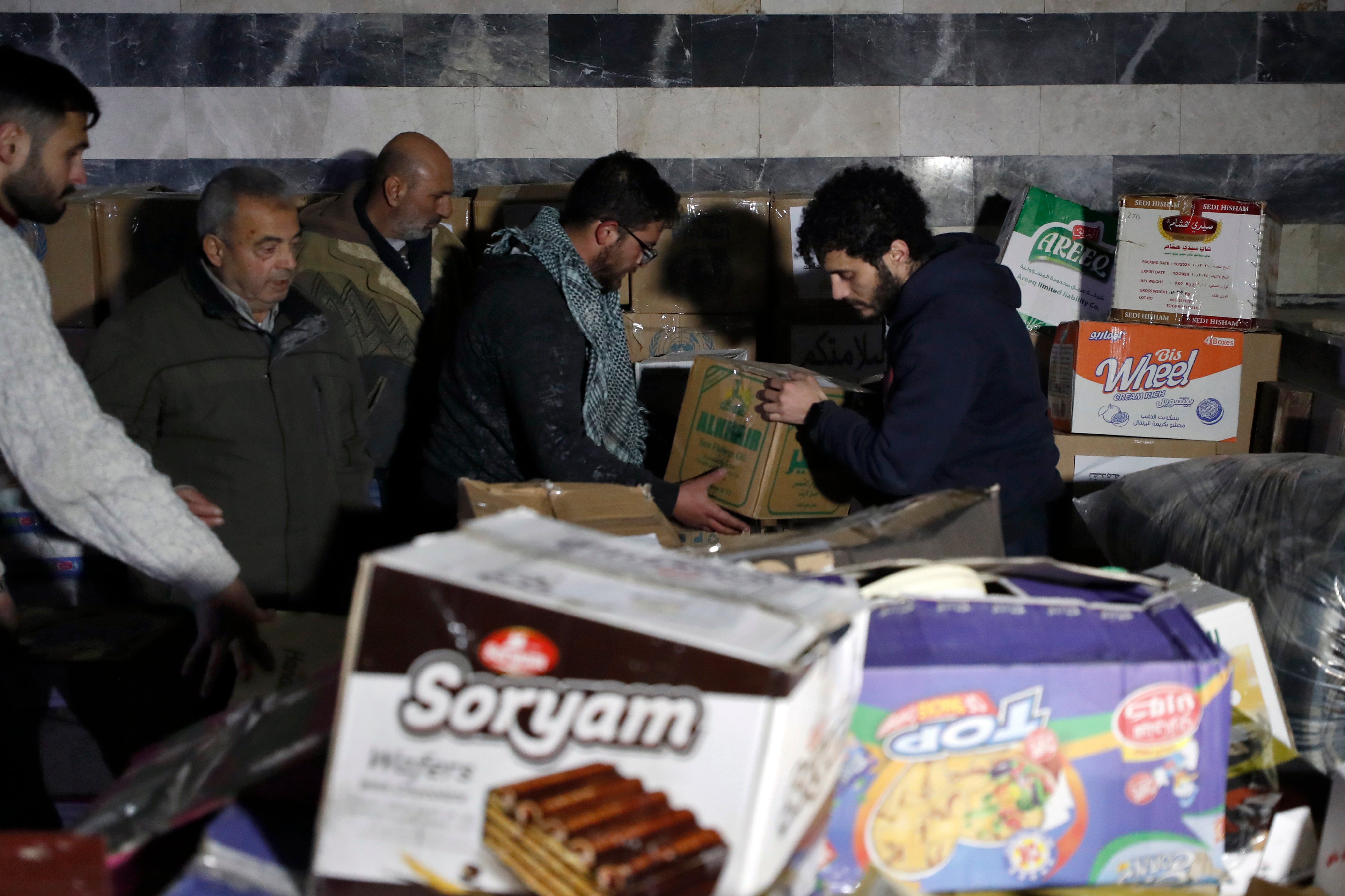 Volunteers carry food boxes to distribute to displaced people following a devastating earthquake, in the coastal city of Latakia, Syria