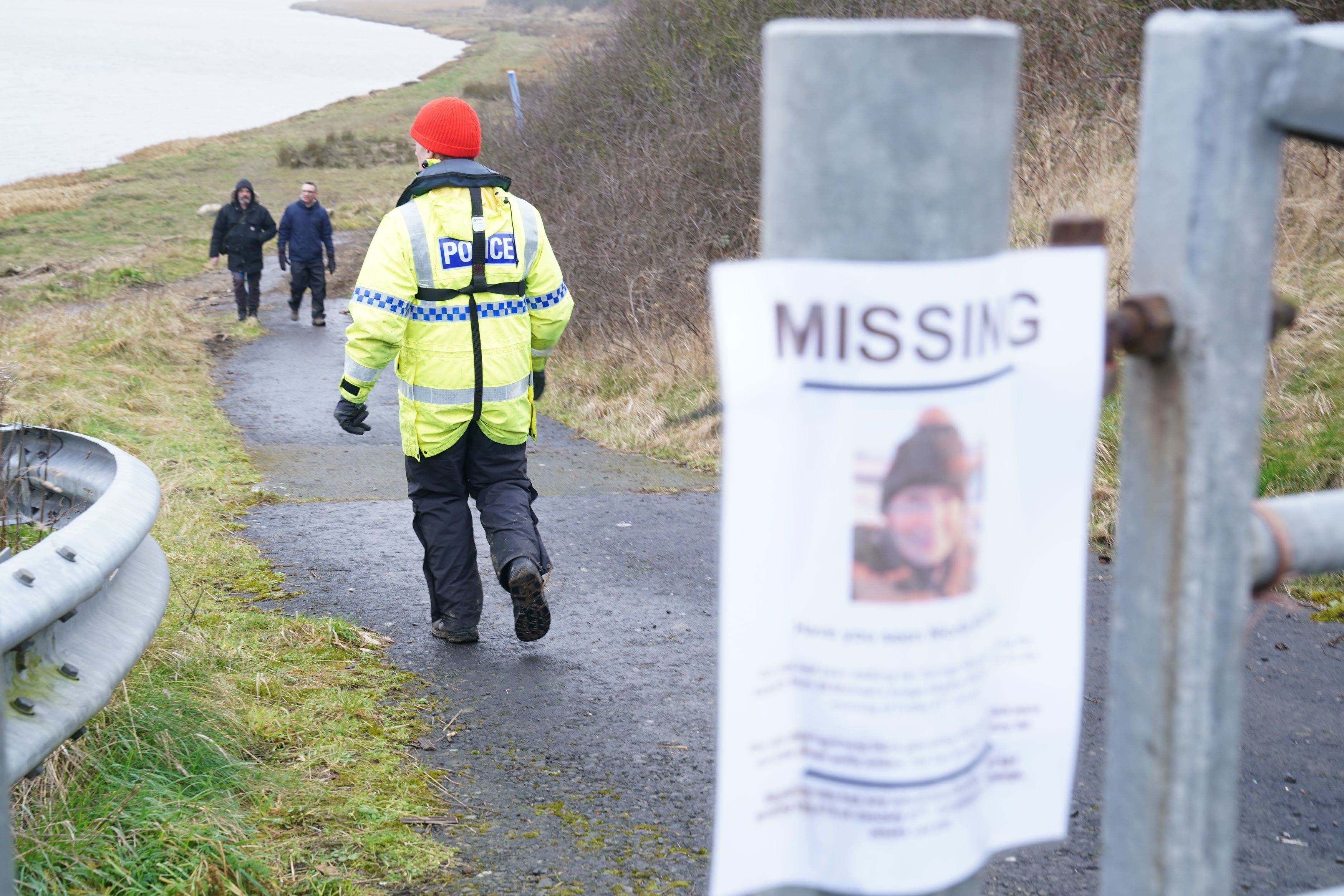 A member of the police search and rescue team waits at Shard Bridge for a boat to come down the River Wyre in Lancashire (Owen Humphreys/PA)