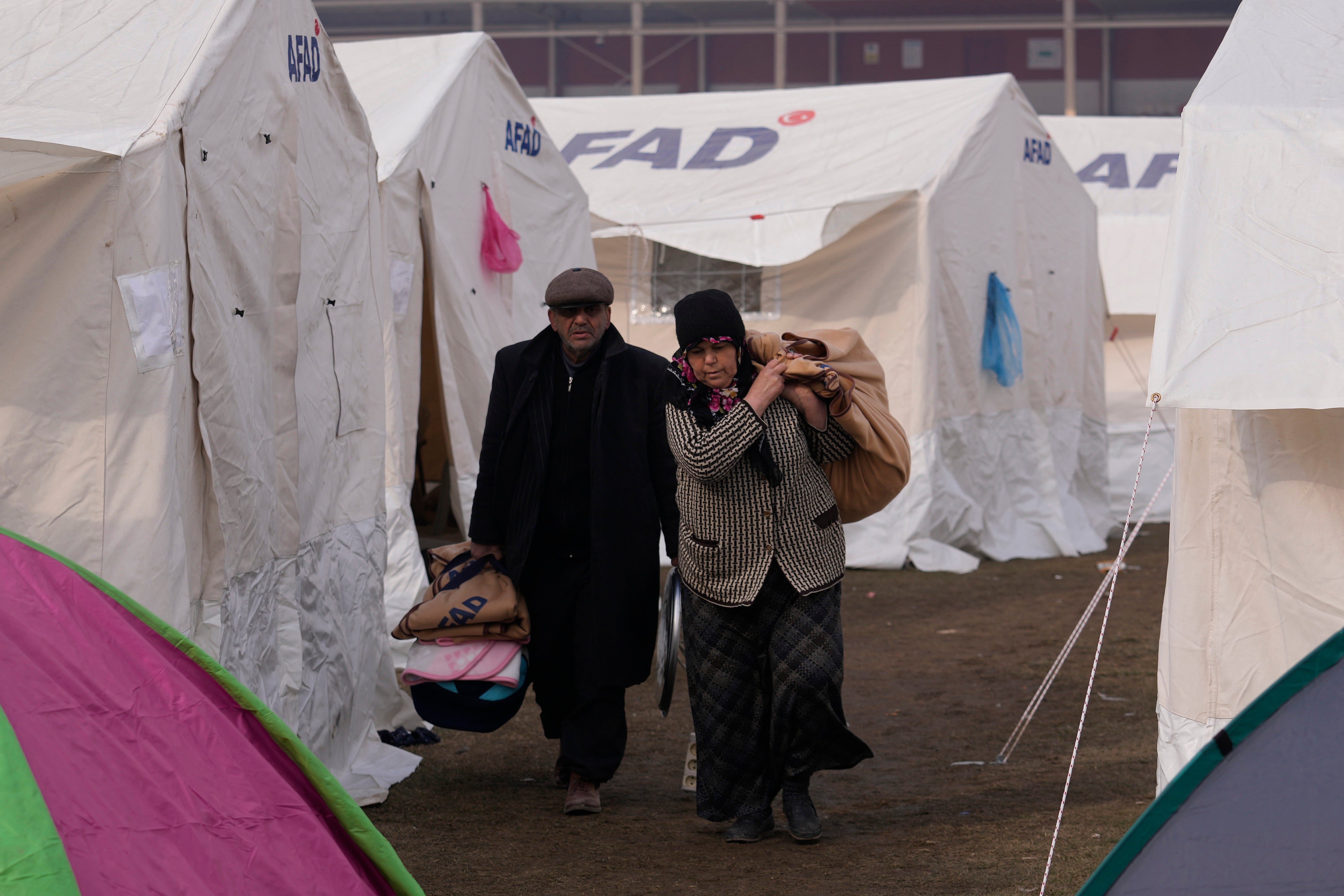 People with their belongings arrive at the tents, in Kharamanmaras, southeastern Turkey