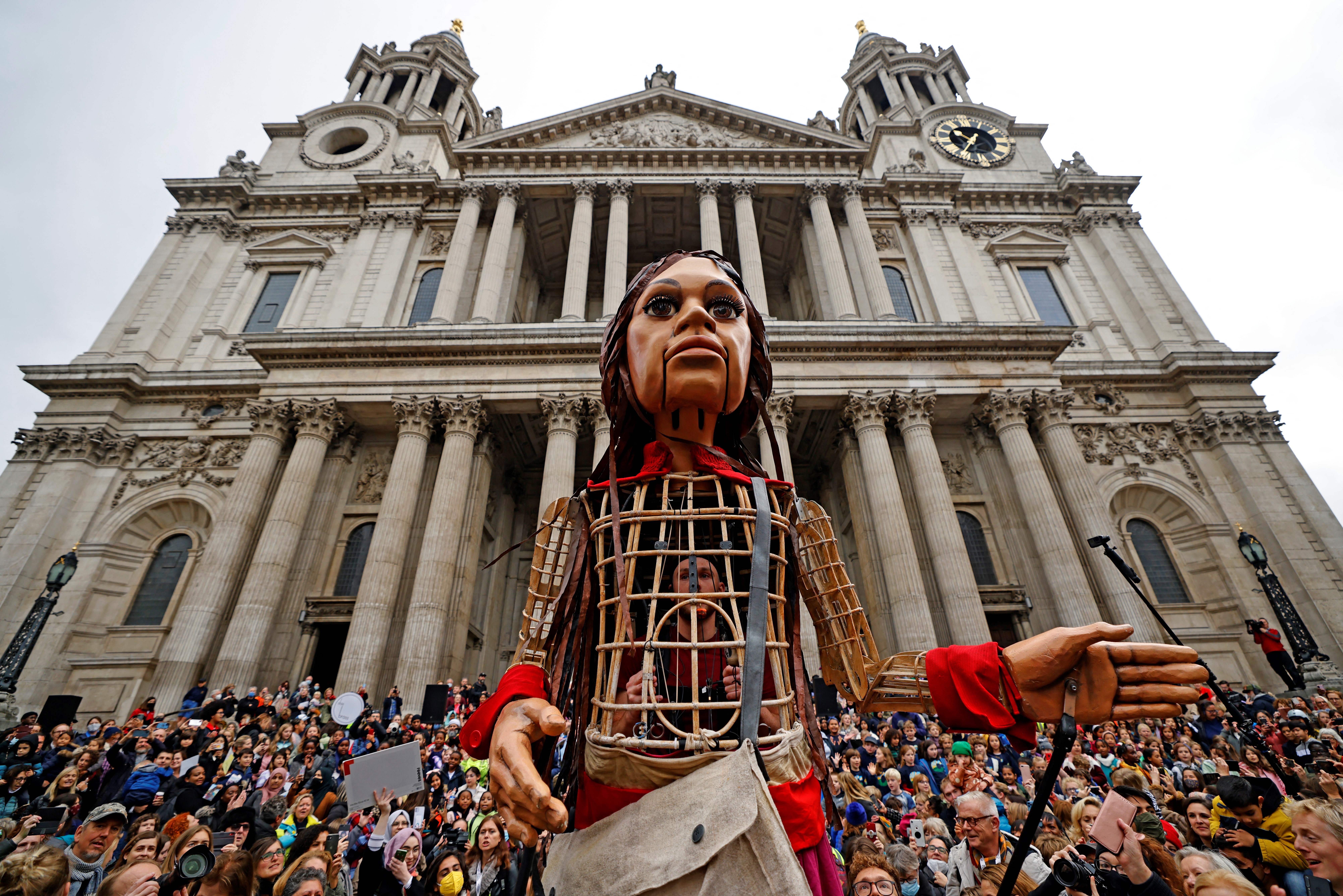 ‘Little Amal’, a giant puppet depicting a Syrian refugee girl, is surrounded by well-wishers outside St Paul’s Cathedral in the City of London