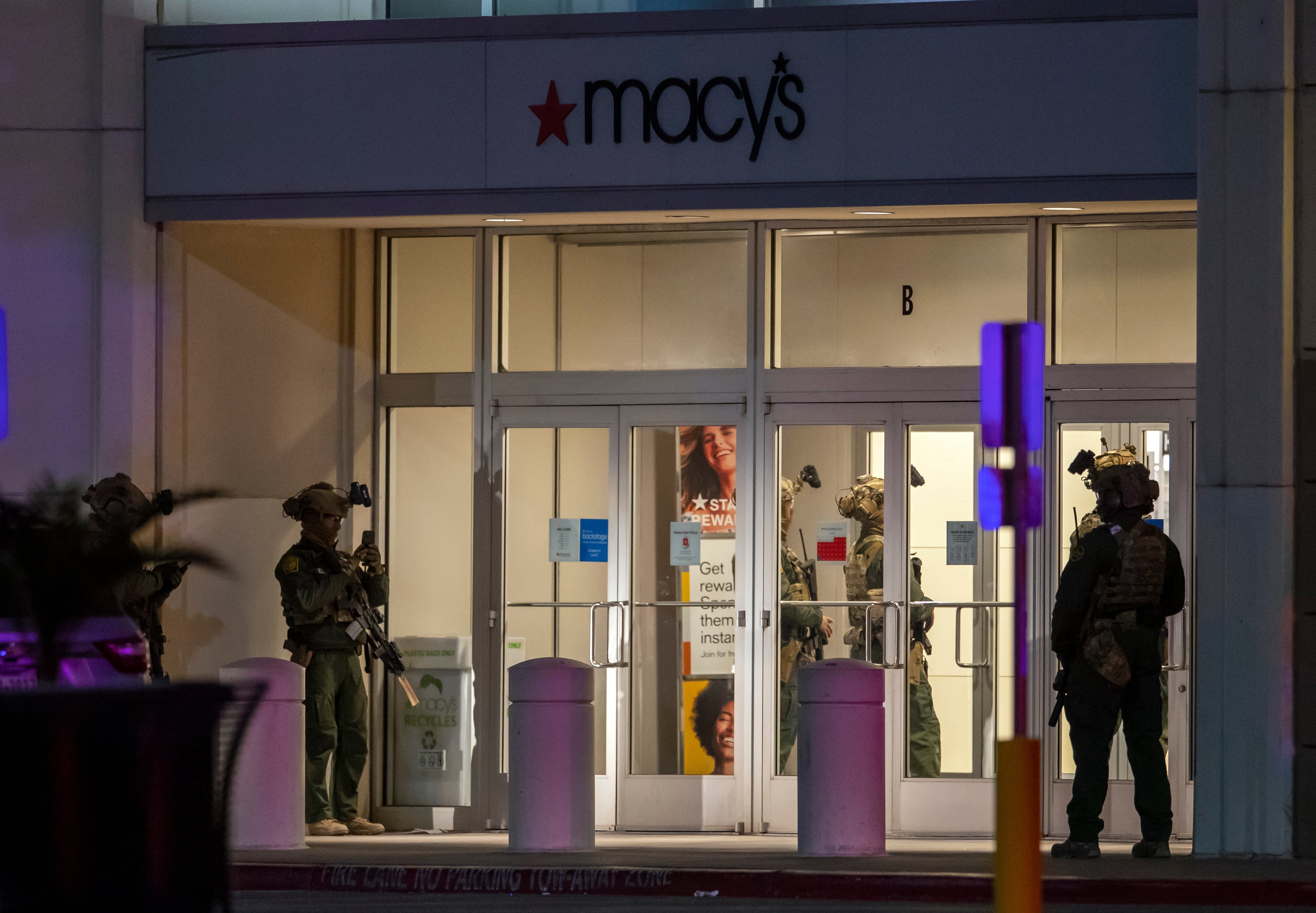 Police officers stand guard at an entrance of the shopping mall