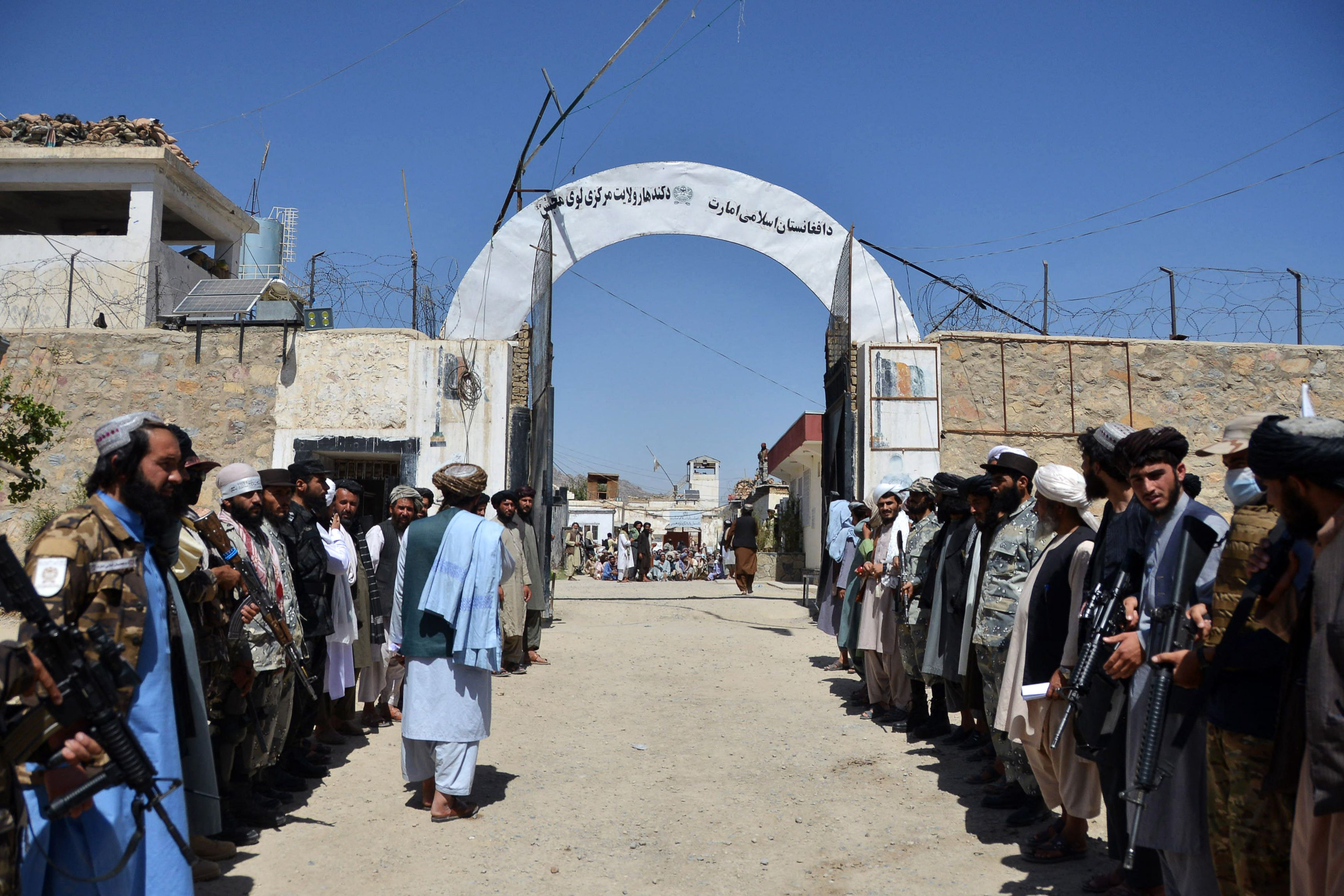 Taliban soldiers stand guard as inmates imprisoned for drug use wait to be released from Kandahar Central Prison in September last year