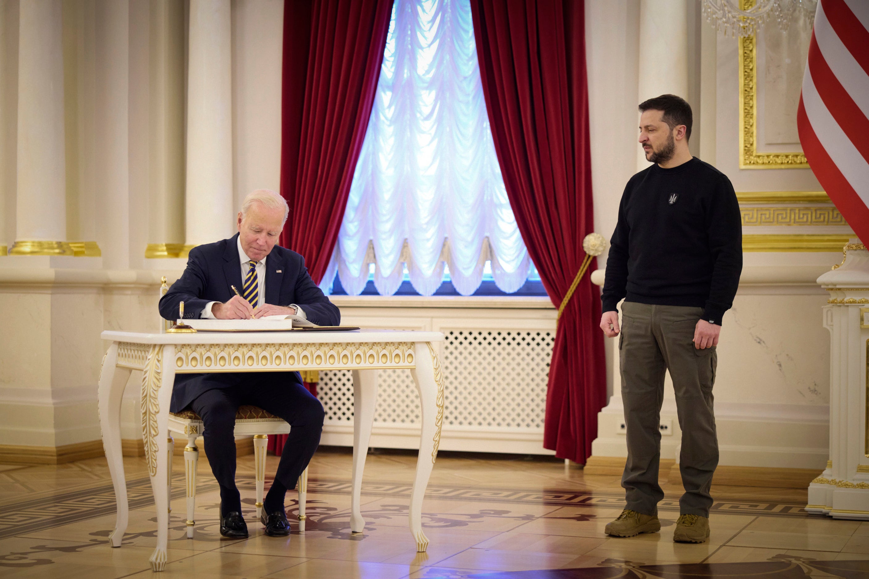 Biden signs a guestbook in the Ukrainian presidential palace