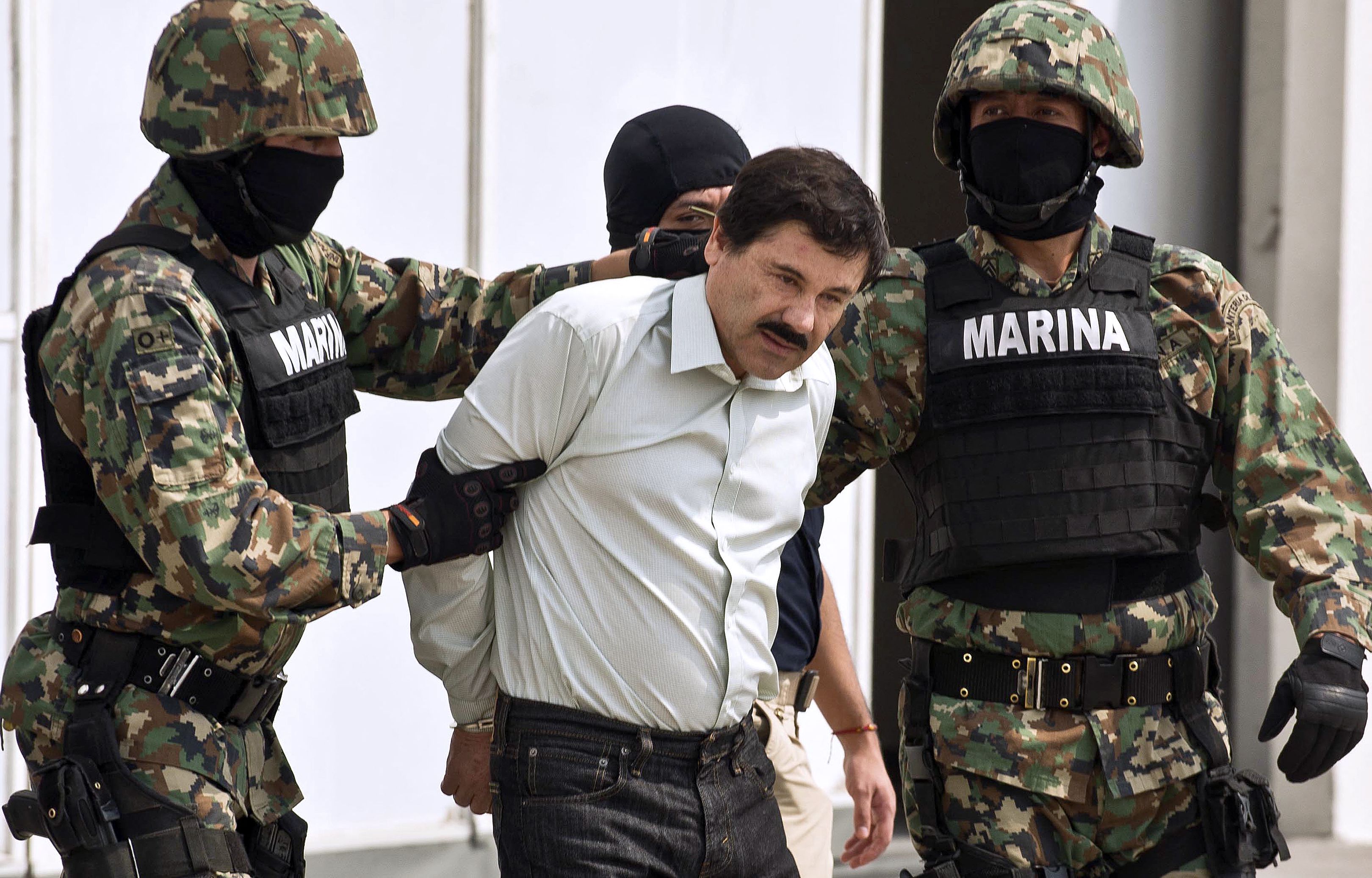 Mexican drug trafficker Joaquin Guzman Loera aka "el Chapo Guzman" (C), is escorted by marines as he is presented to the press on February 22, 2014 in Mexico City.