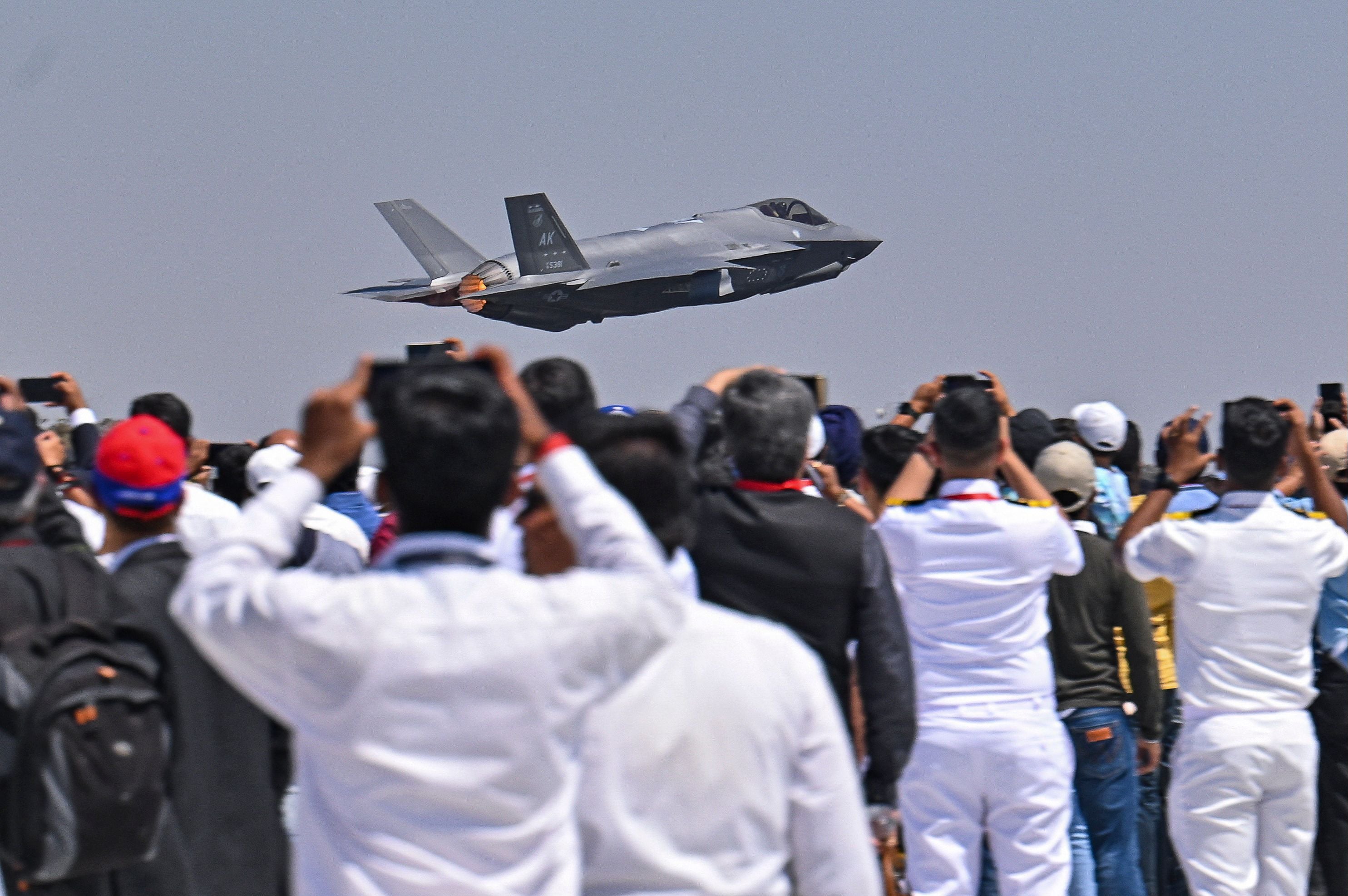 Spectators watch as a US Air Force’s (USAF) fifth-generation supersonic multirole F-35 fighter jet flies past during a flying display on the second day of the 14th edition of Aero India 2023 at the Yelahanka Air Force Station in Bengaluru