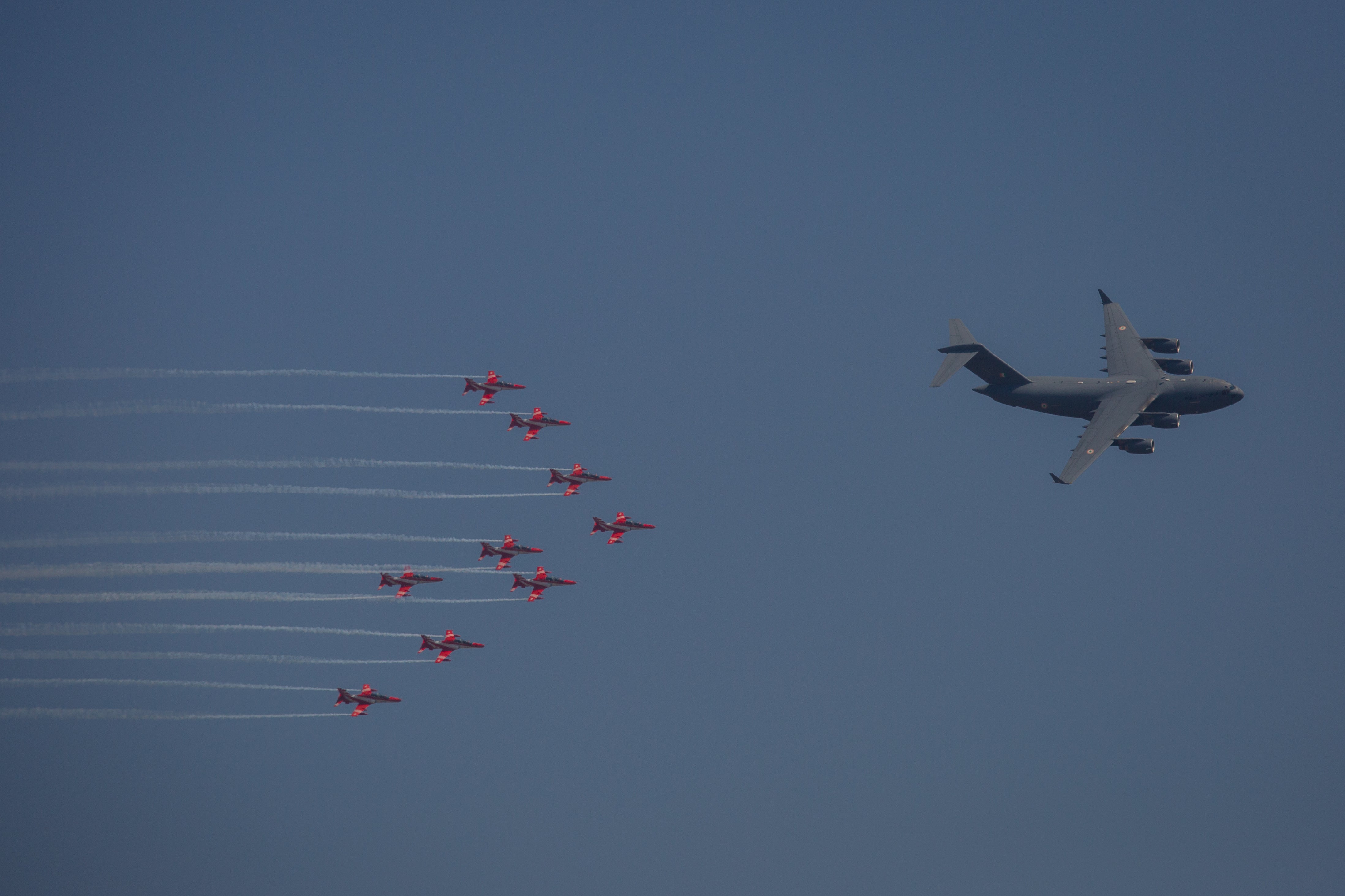 The Surya Kiran Aerobatic Team (SKAT) follows an Indian Air Force C-17-Globemaster as they perform during the inauguration of the Aero India 2023 at the Yelahanka Air Force Station in Bengaluru