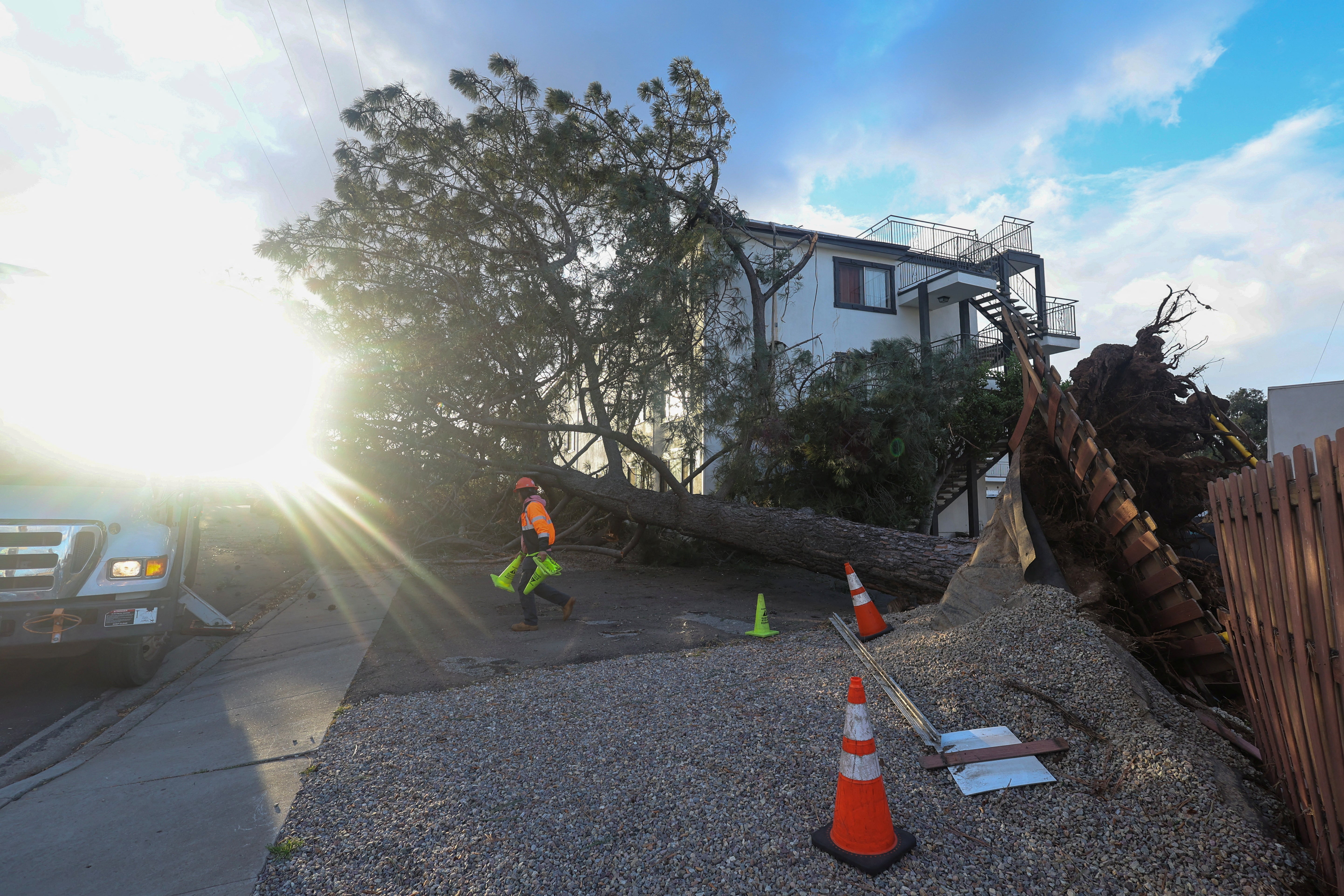 An emergency worker assesses the damage after a large tree was blown into an apartment building during a winter storm in San Diego, California on Wednesday (REUTERS/Mike Blake)