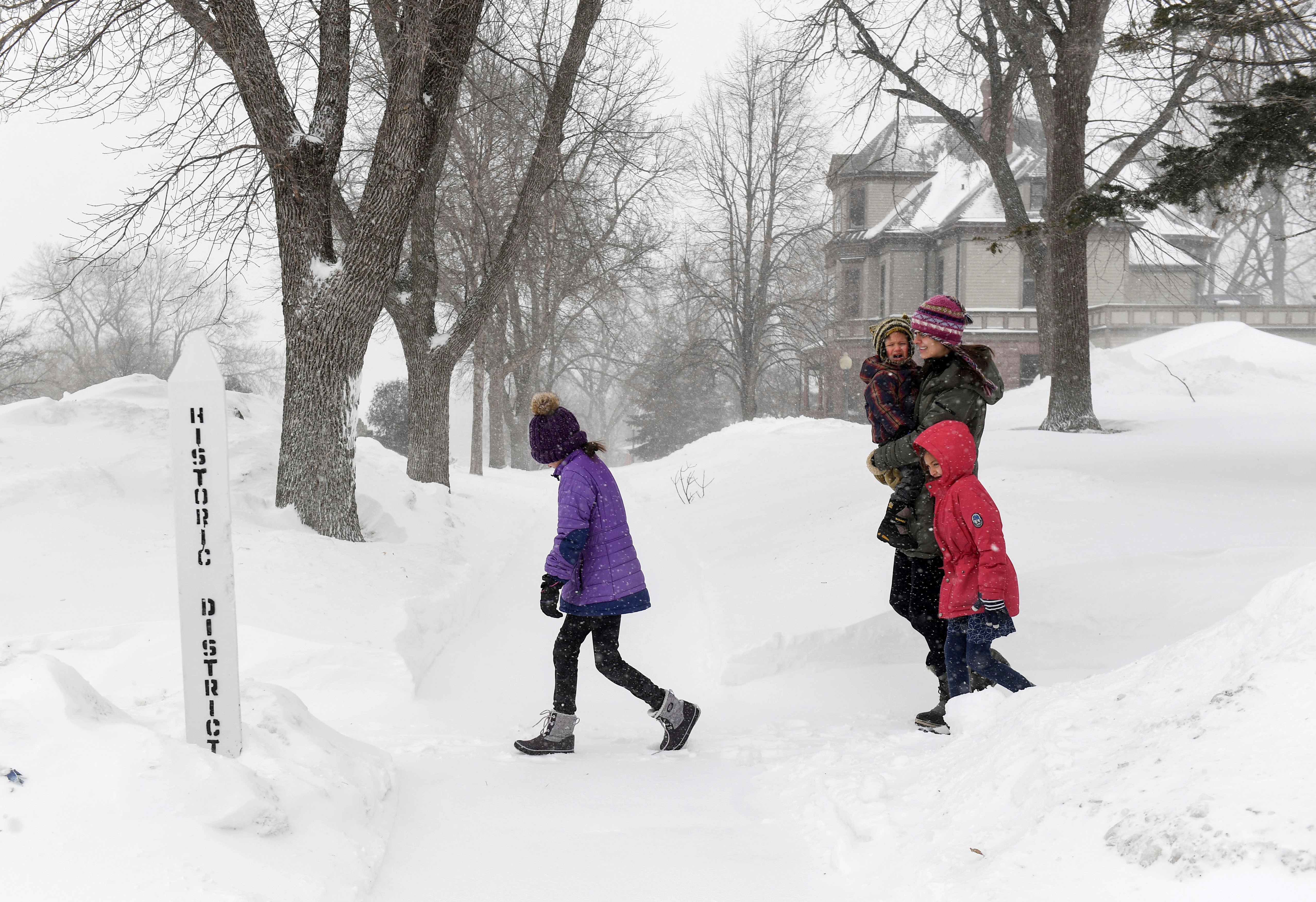 A family walks through blowing snow as weather conditions worsen on Wednesday, Feb. 22, 2023, in Sioux Falls, South Dakota (Erin Woodiel /The Argus Leader via AP)