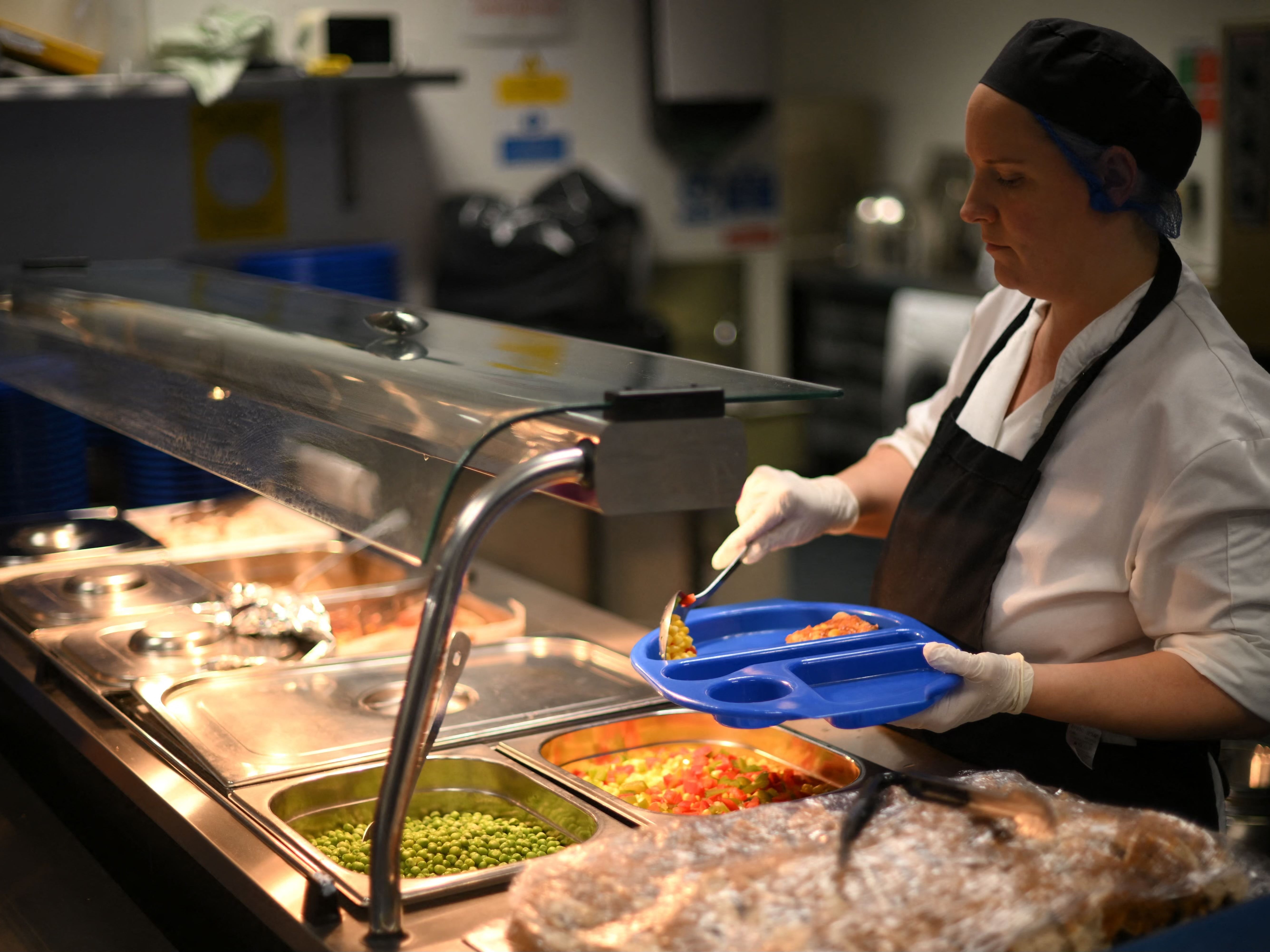 A school canteen chef serves children during their lunch break