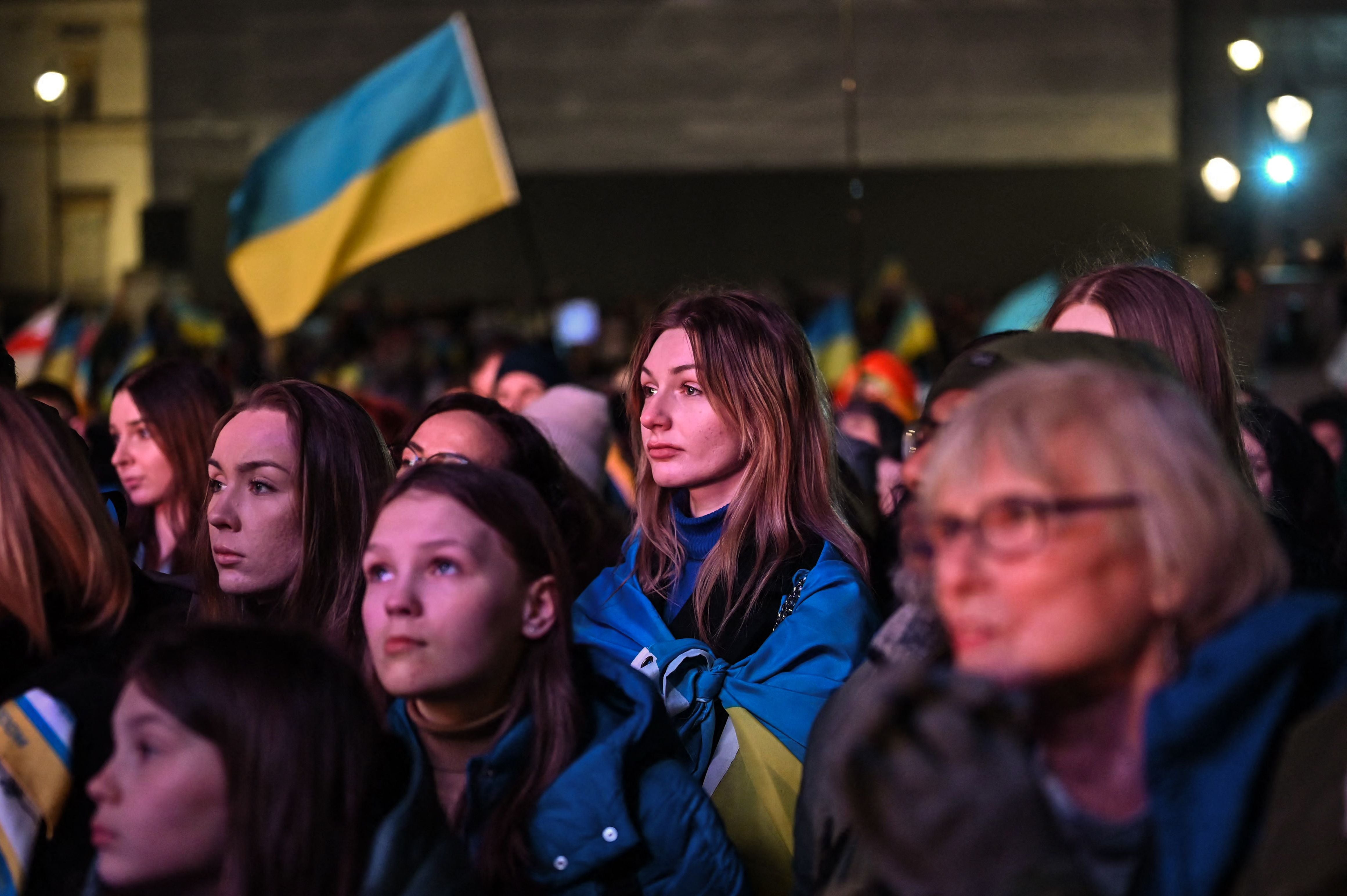 People wave Ukrainian flags as they attend a vigil in Trafalgar Square, central London